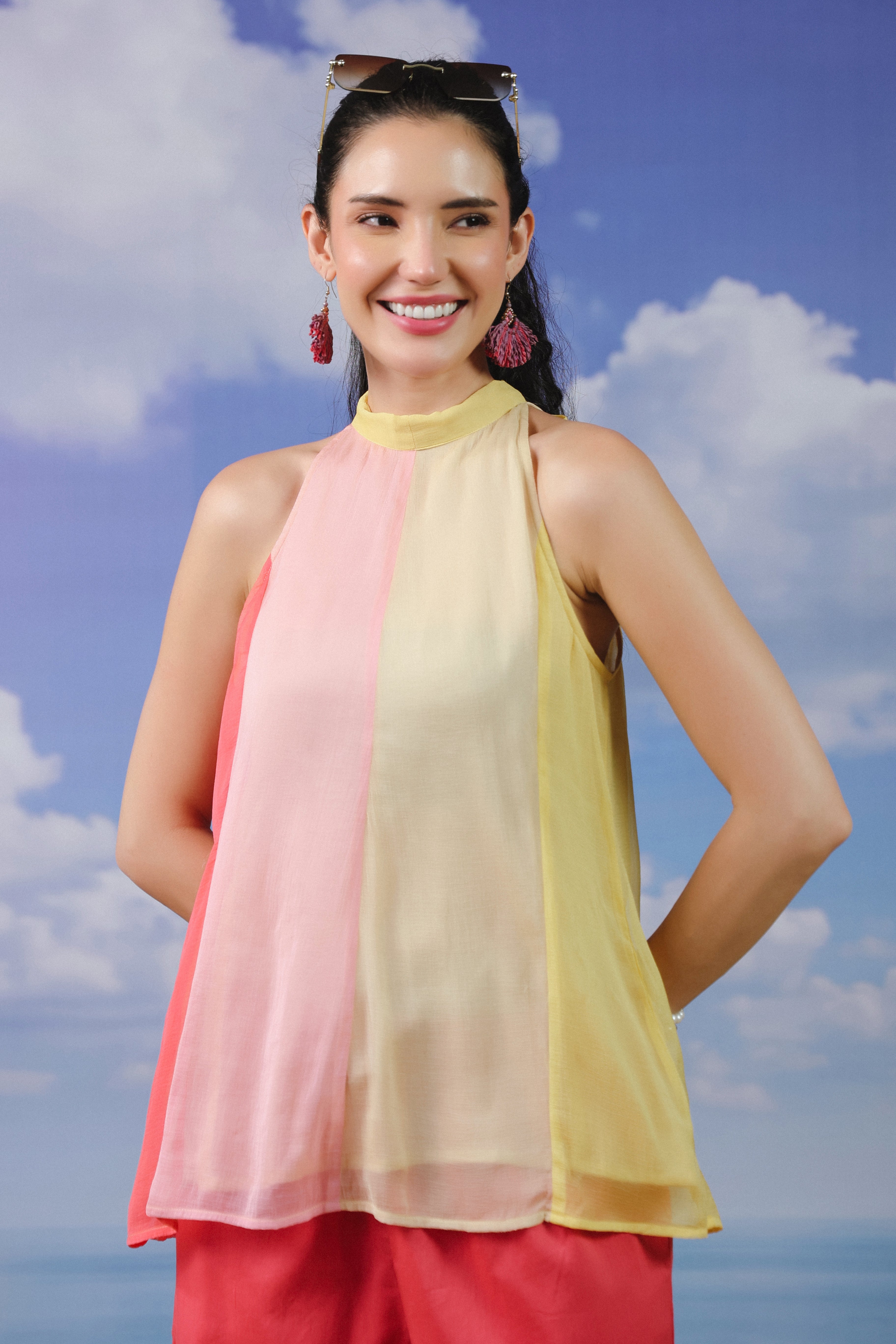 Woman wearing a pastel pink and yellow colorblock halter neck sleeveless top paired with coral pink shorts, creating a stylish summer co-ord outfit for beach vacations and casual wear.