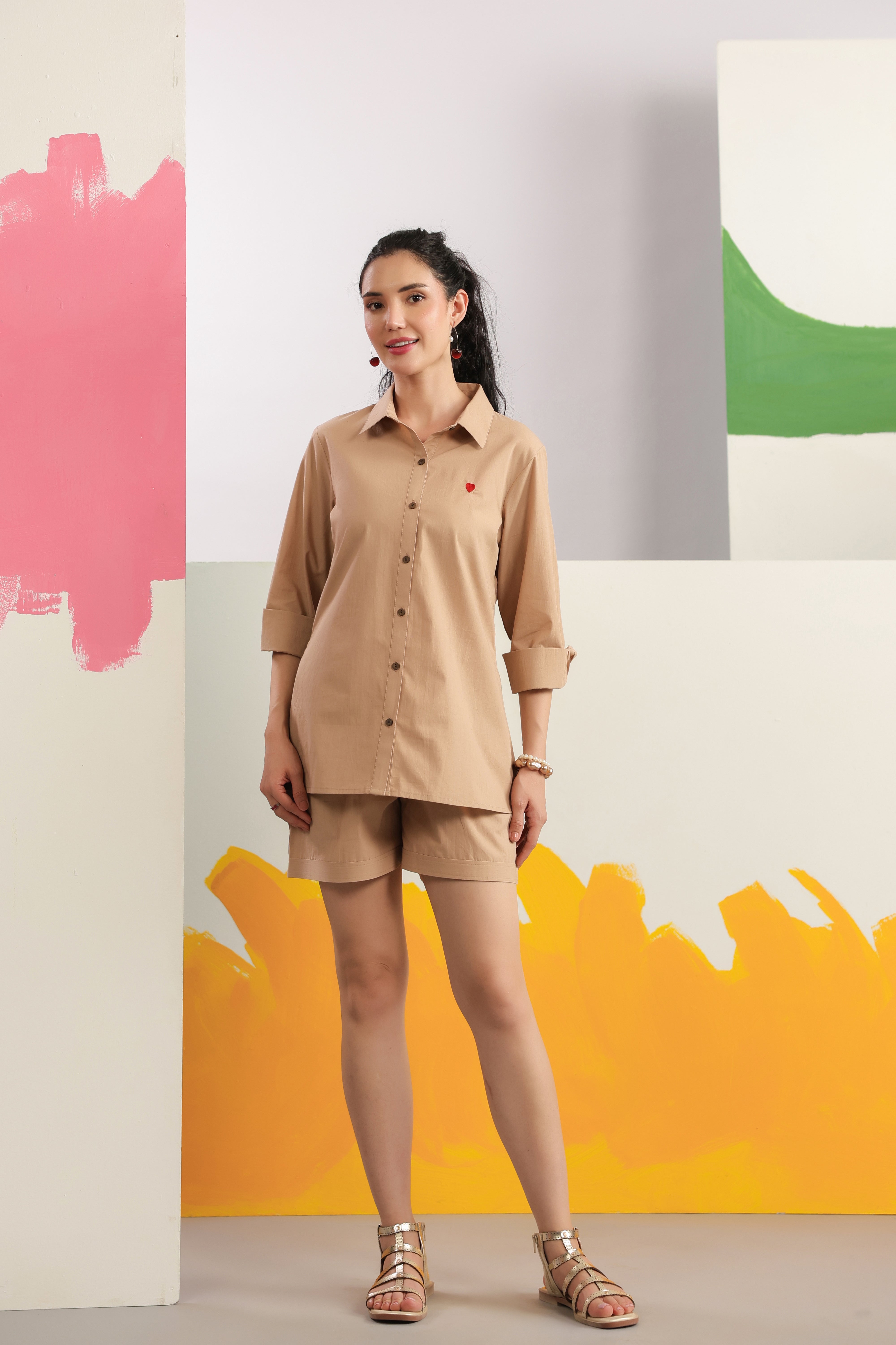Woman wearing a beige cotton shirt and shorts co-ord set featuring a collared button-down shirt with full sleeves and matching shorts, styled for casual summer fashion.
