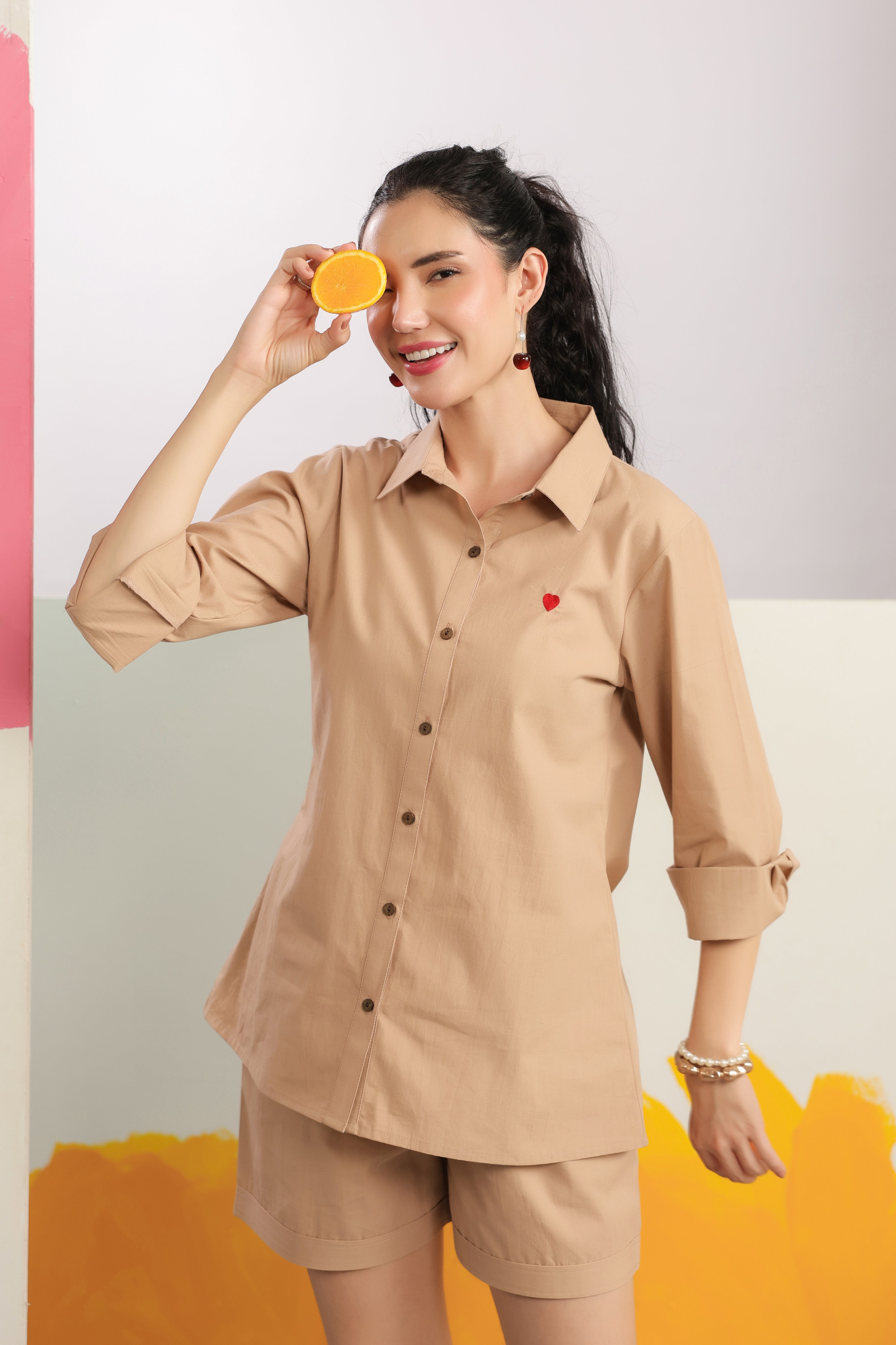 Woman wearing a beige cotton shirt and shorts co-ord set featuring a collared button-down shirt with full sleeves and matching shorts, styled for casual summer fashion.