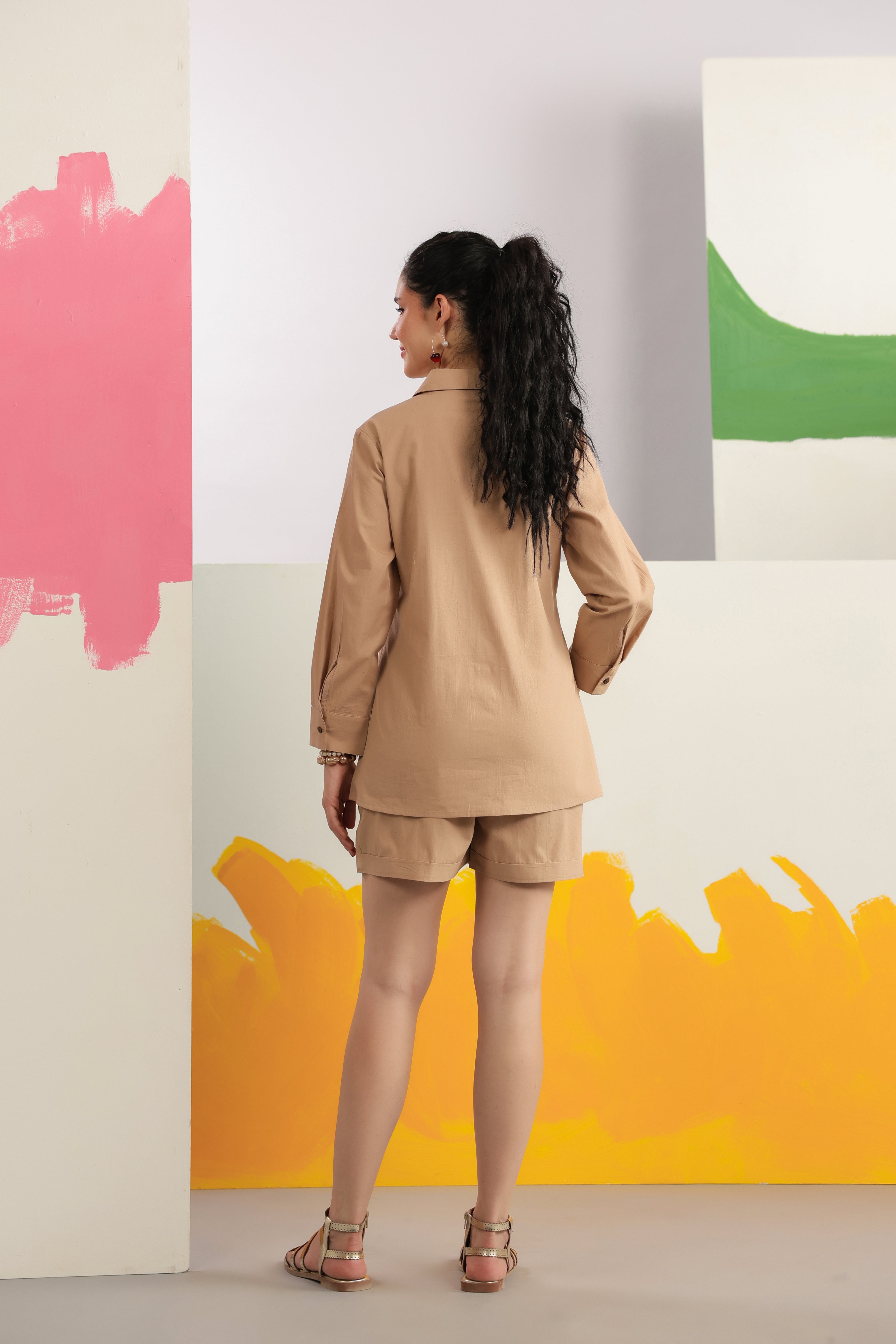 Woman wearing a beige cotton shirt and shorts co-ord set featuring a collared button-down shirt with full sleeves and matching shorts, styled for casual summer fashion.