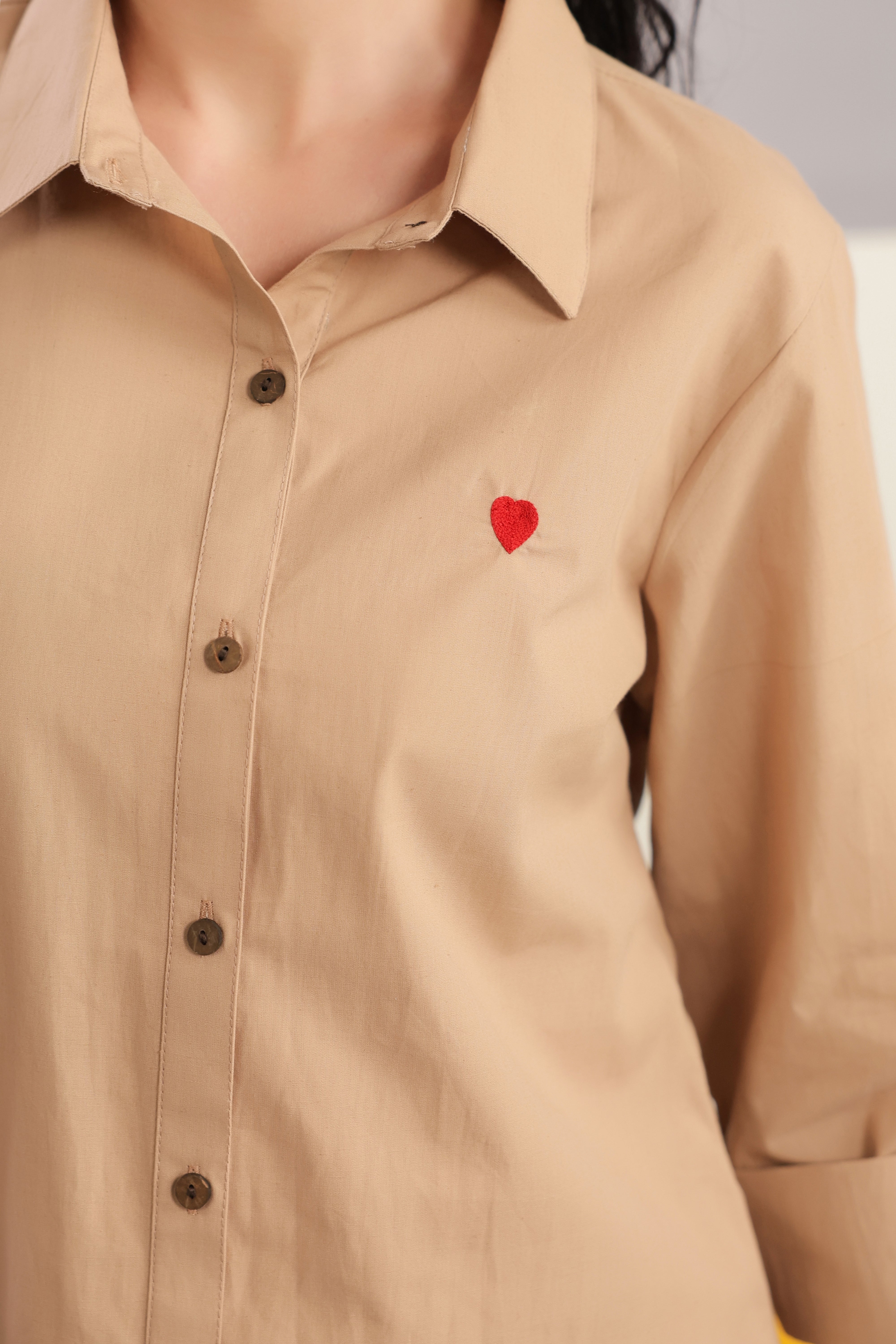 Woman wearing a beige cotton shirt and shorts co-ord set featuring a collared button-down shirt with full sleeves and matching shorts, styled for casual summer fashion.