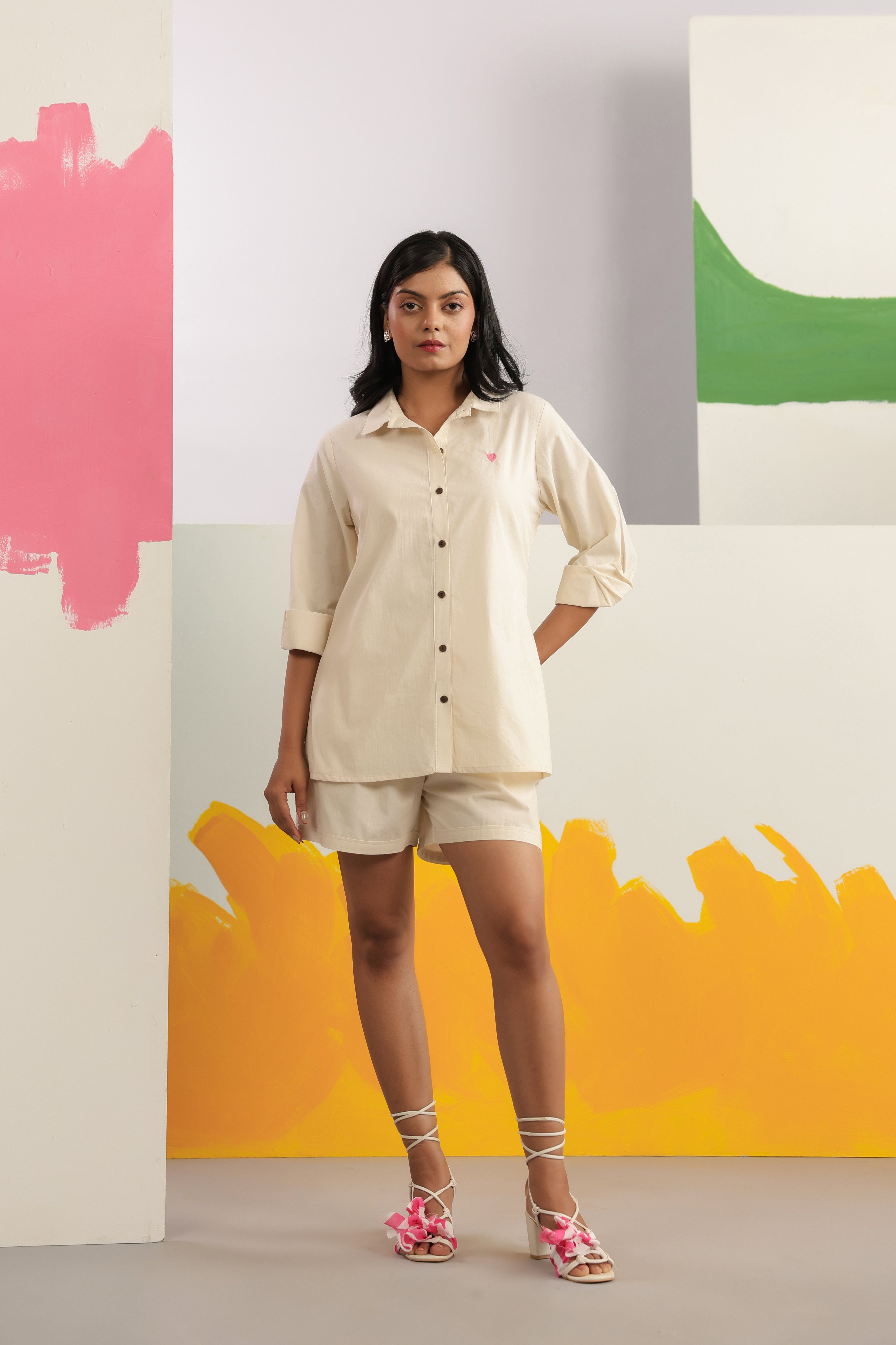 Woman wearing an ivory cotton shirt and shorts co-ord set featuring a classic collared button-down shirt with full sleeves and matching relaxed-fit shorts, creating a minimalist and elegant look ideal for casual outings, vacations, resort wear, and everyday summer styling.