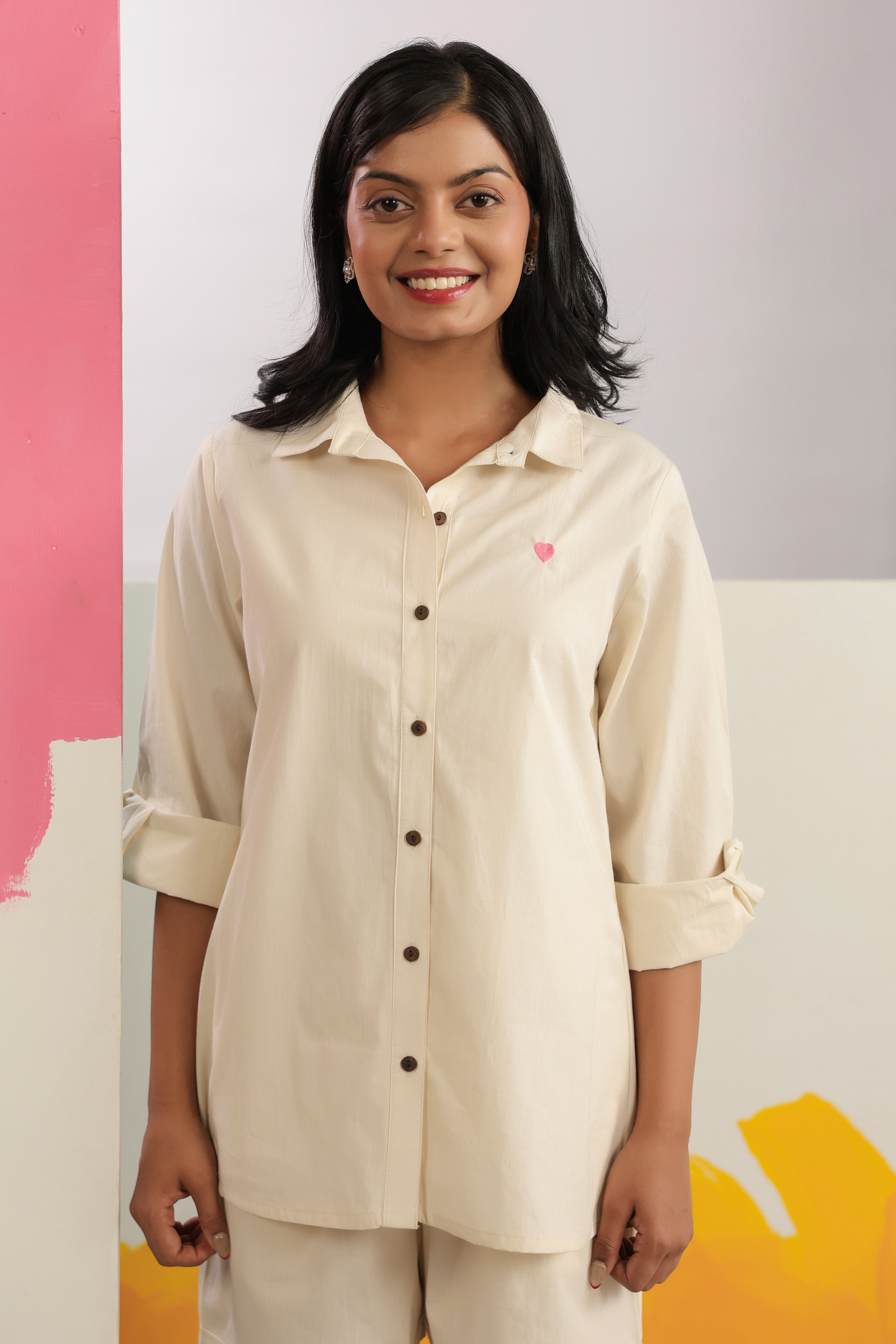 Woman wearing an ivory cotton shirt and shorts co-ord set featuring a classic collared button-down shirt with full sleeves and matching relaxed-fit shorts, creating a minimalist and elegant look ideal for casual outings, vacations, resort wear, and everyday summer styling.