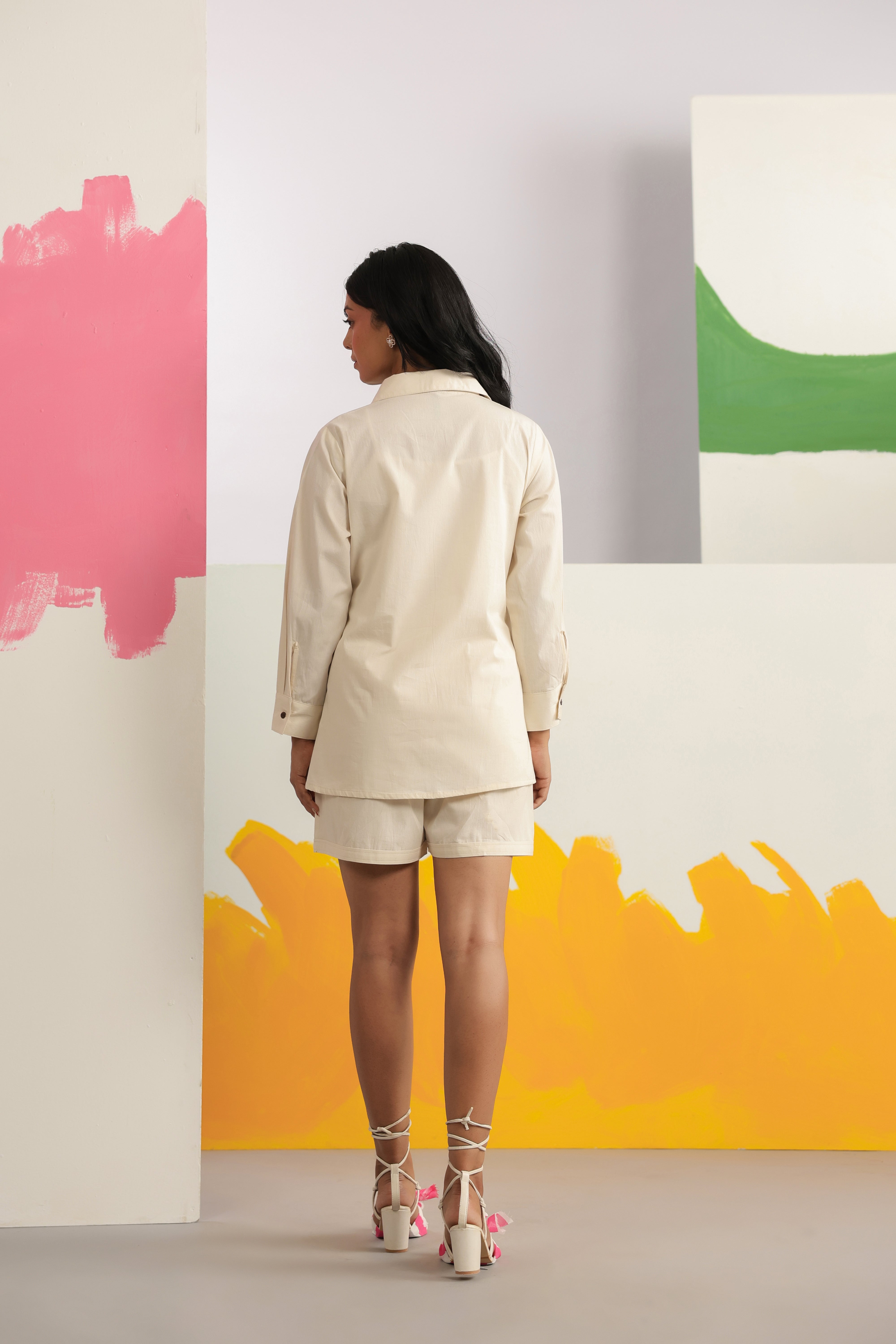 Woman wearing an ivory cotton shirt and shorts co-ord set featuring a classic collared button-down shirt with full sleeves and matching relaxed-fit shorts, creating a minimalist and elegant look ideal for casual outings, vacations, resort wear, and everyday summer styling.
