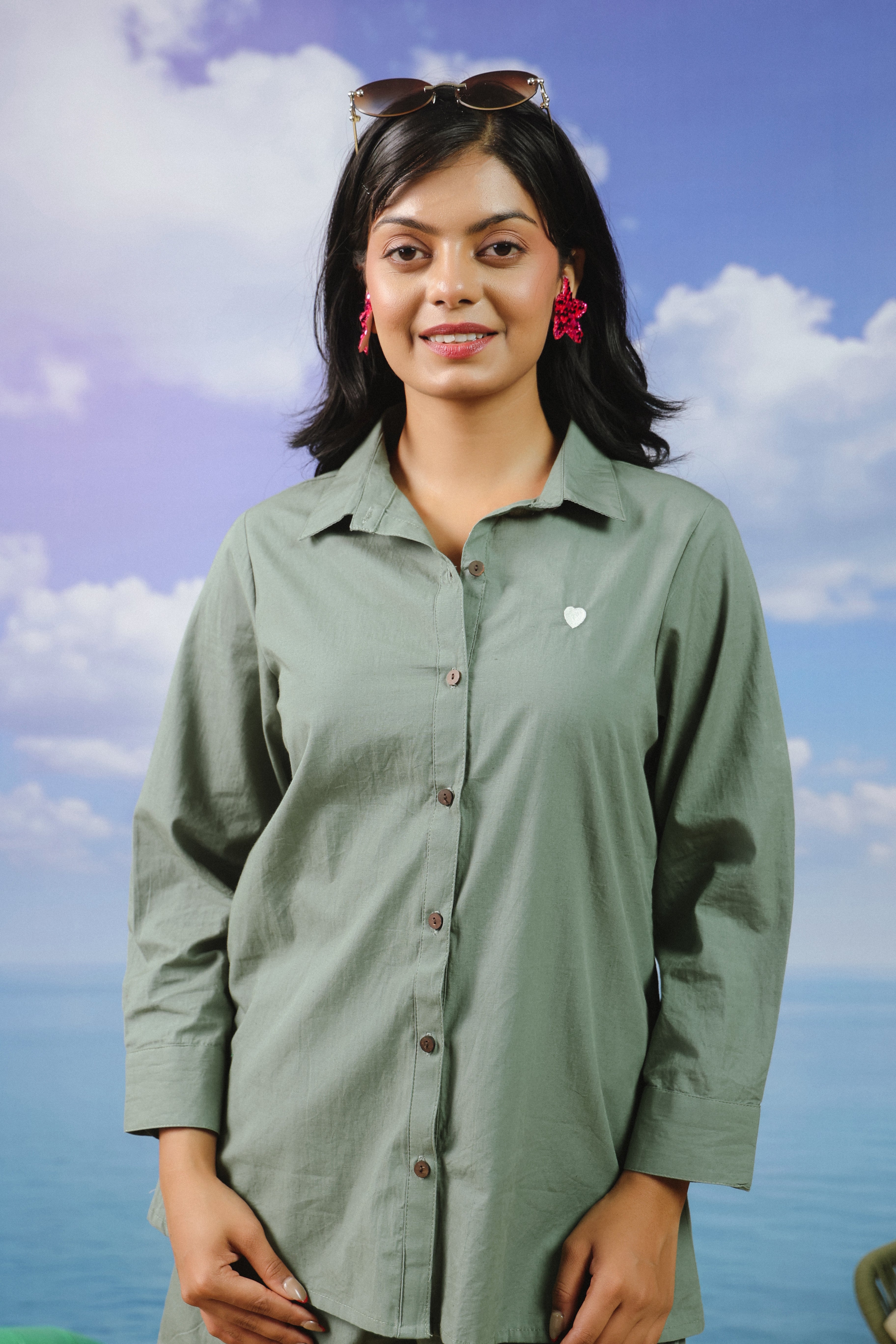 Woman wearing a sage green cotton shirt and shorts co-ord set featuring a classic button-down collared shirt with full sleeves and matching relaxed-fit shorts, ideal for casual outings, vacations, resort wear, and everyday summer styling.
