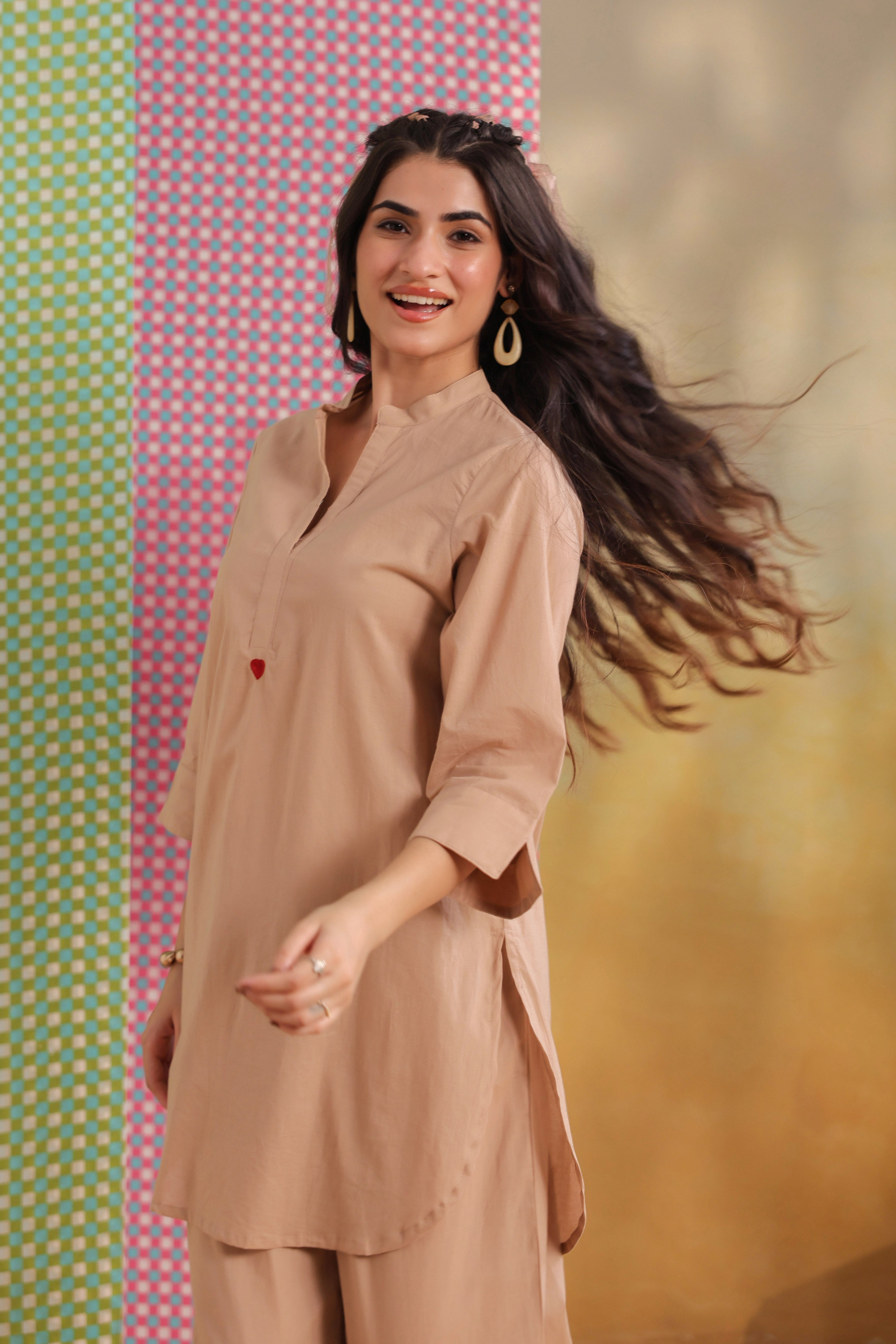Woman wearing a beige cotton co-ord set featuring a relaxed-fit straight kurta with a mandarin V-neck and matching elasticated jogger pants, offering a minimalist and elegant look for casual, office, travel, and everyday wear.