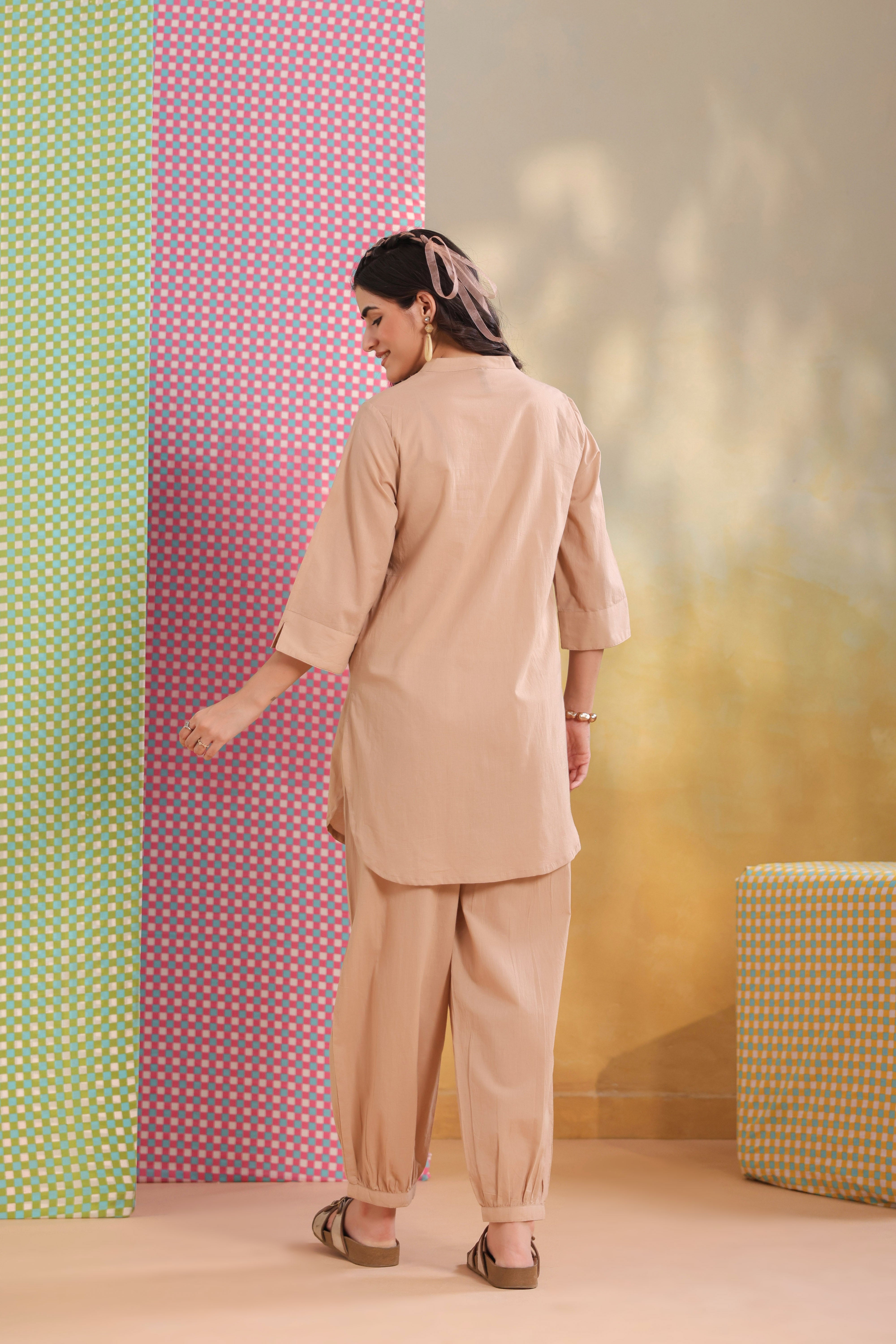 Woman wearing a beige cotton co-ord set featuring a relaxed-fit straight kurta with a mandarin V-neck and matching elasticated jogger pants, offering a minimalist and elegant look for casual, office, travel, and everyday wear.