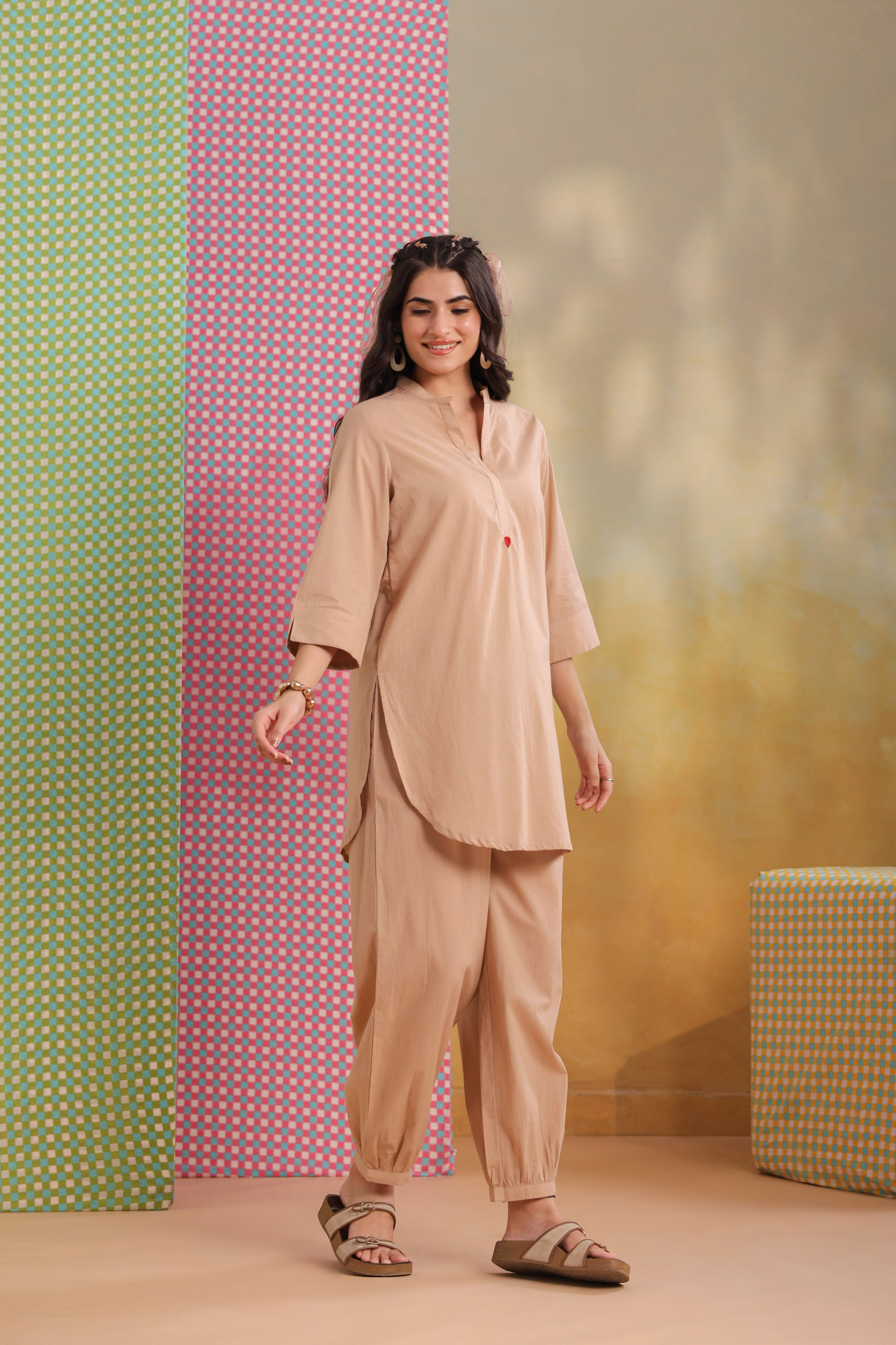 Woman wearing a beige cotton co-ord set featuring a relaxed-fit straight kurta with a mandarin V-neck and matching elasticated jogger pants, offering a minimalist and elegant look for casual, office, travel, and everyday wear.
