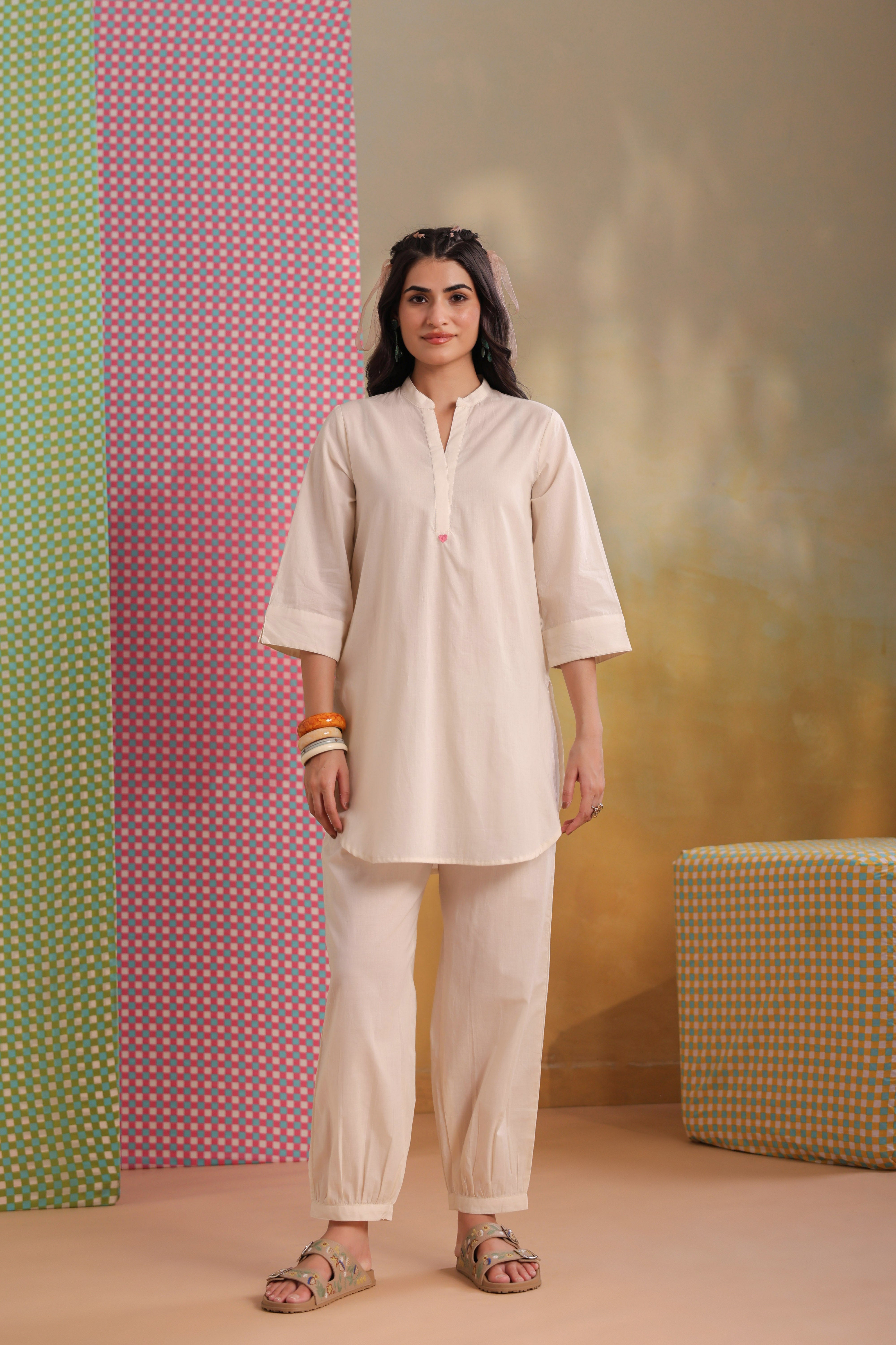 Woman wearing an ivory cotton co-ord set featuring a relaxed-fit straight kurta with a mandarin V-neck and matching elasticated jogger pants, offering a minimalist and elegant look for casual, office, and everyday wear.