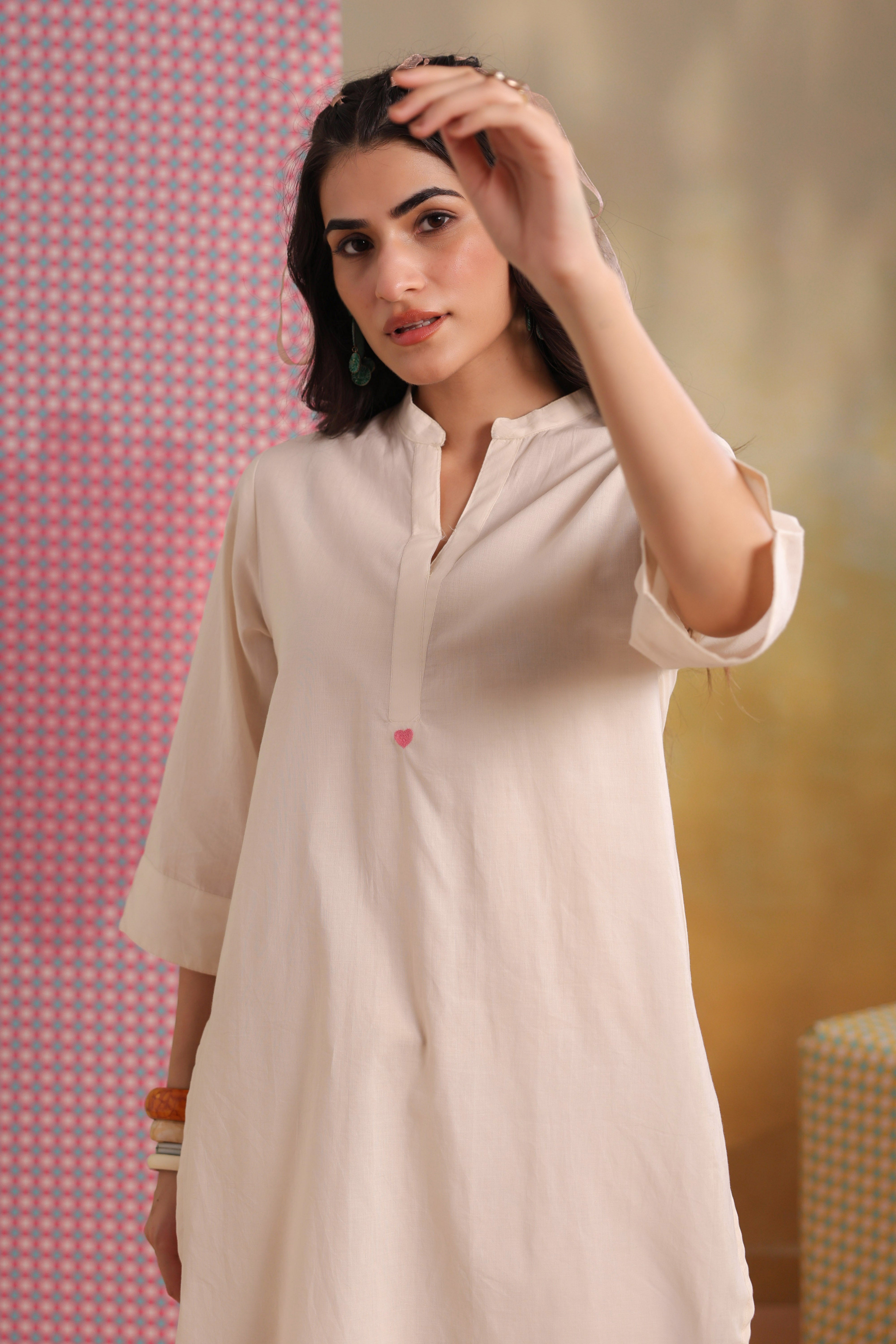 Woman wearing an ivory cotton co-ord set featuring a relaxed-fit straight kurta with a mandarin V-neck and matching elasticated jogger pants, offering a minimalist and elegant look for casual, office, and everyday wear.