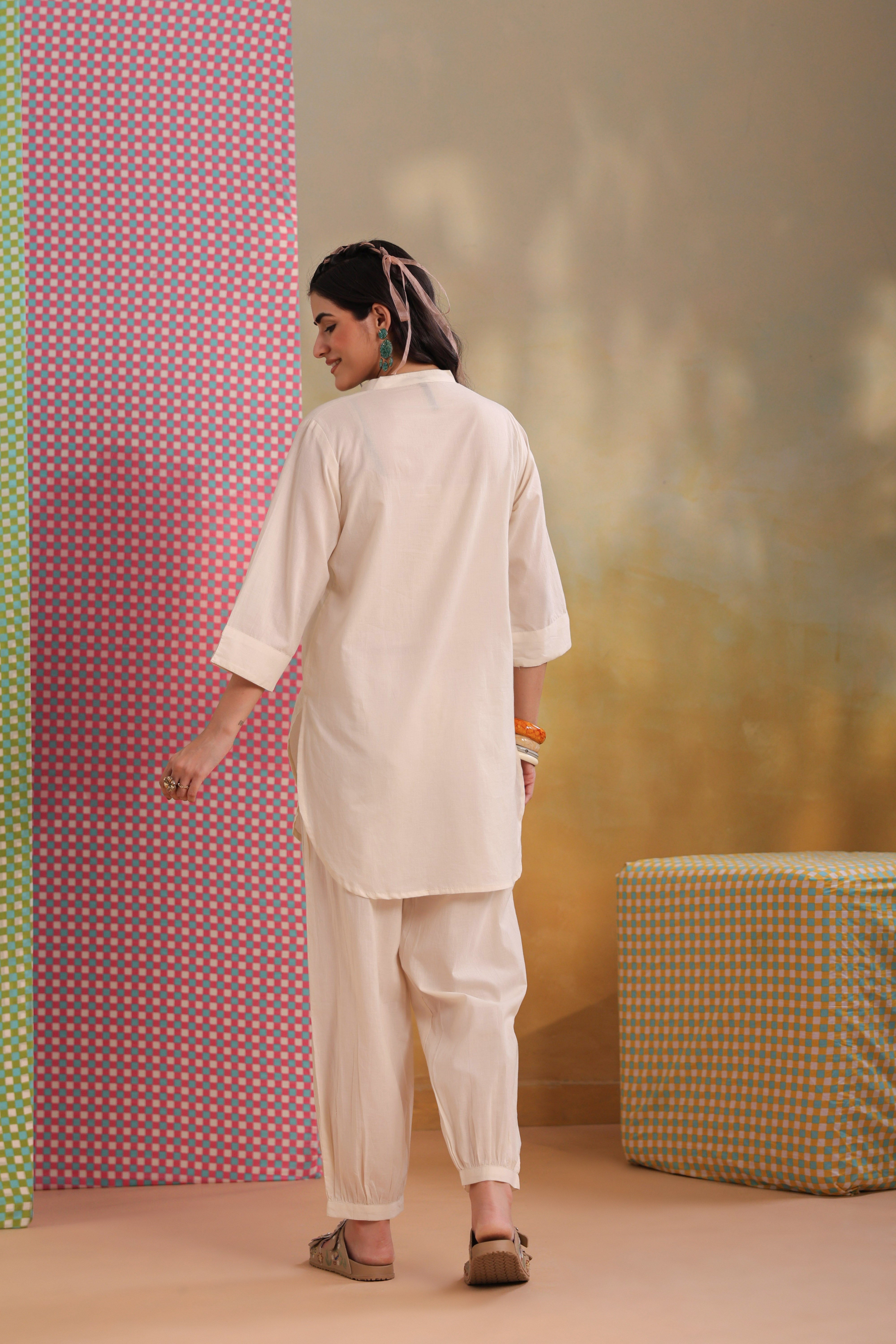 Woman wearing a beige cotton co-ord set featuring a relaxed-fit straight kurta with a mandarin V-neck and matching elasticated jogger pants, offering a minimalist and elegant look for casual, office, travel, and everyday wear.
