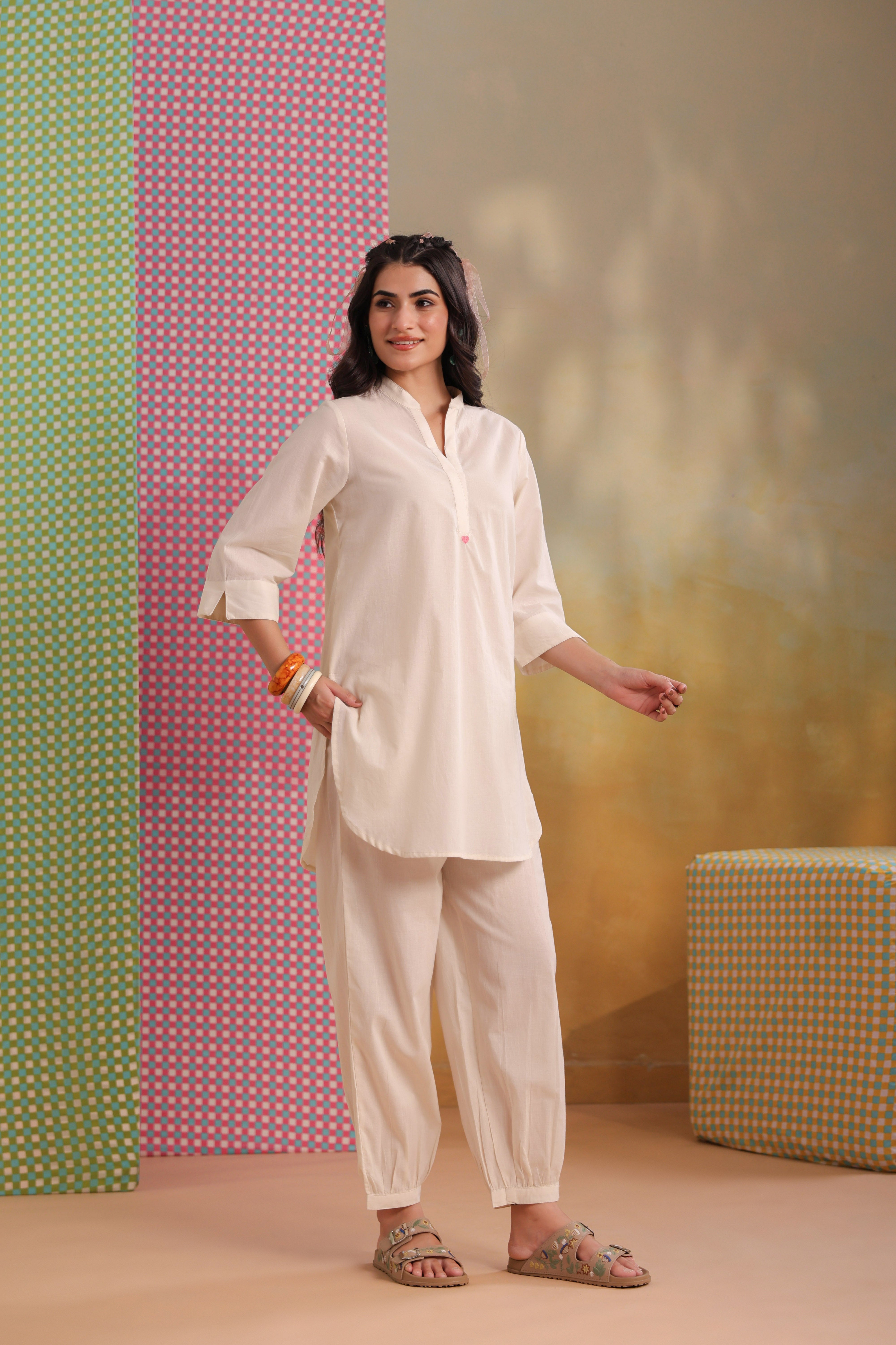 Woman wearing a beige cotton co-ord set featuring a relaxed-fit straight kurta with a mandarin V-neck and matching elasticated jogger pants, offering a minimalist and elegant look for casual, office, travel, and everyday wear.