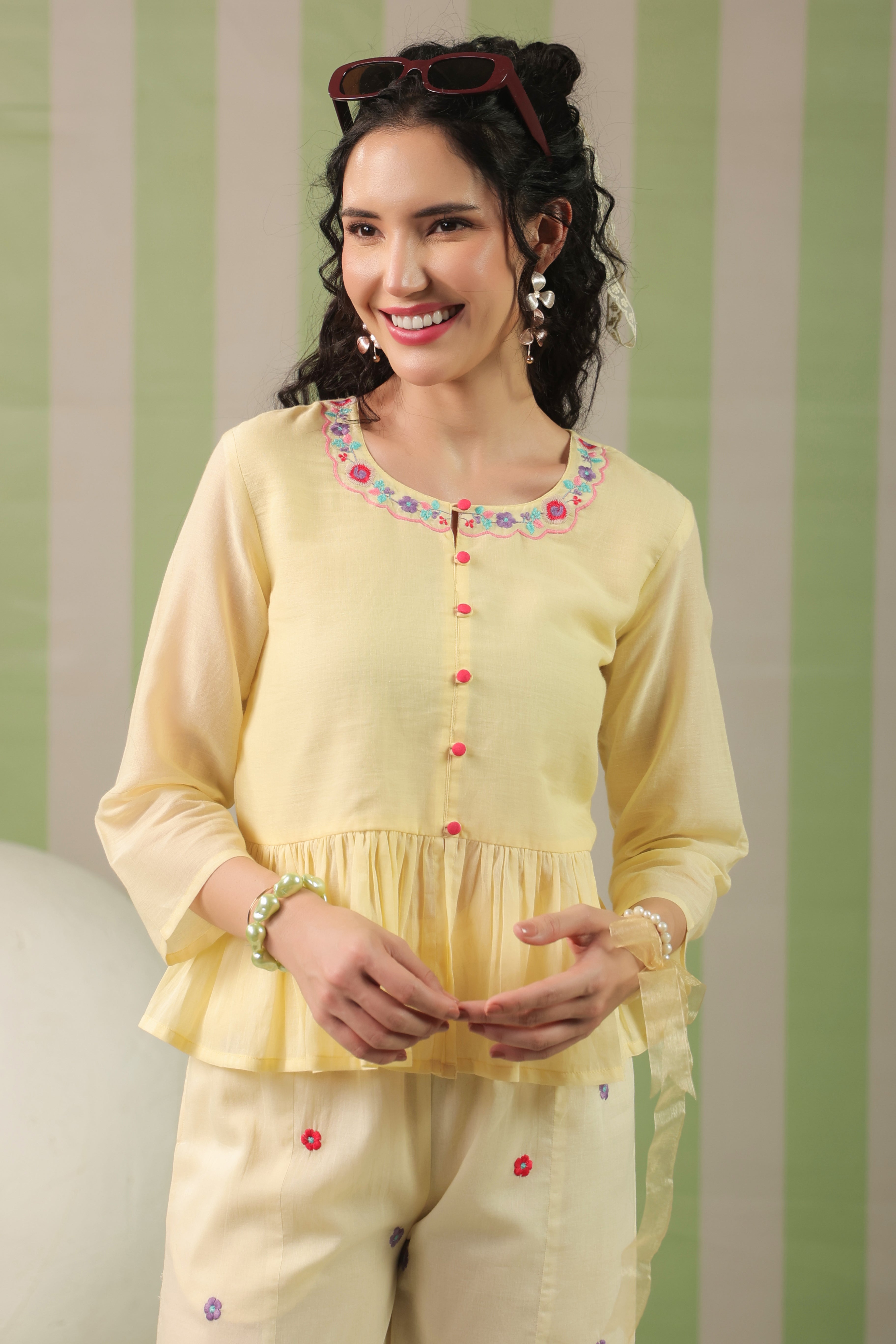 Woman wearing a blush yellow embroidered peplum co-ord set with wide-leg palazzo pants, featuring a floral embroidered neckline and relaxed elegant fit. Perfect for casual and festive occasions.