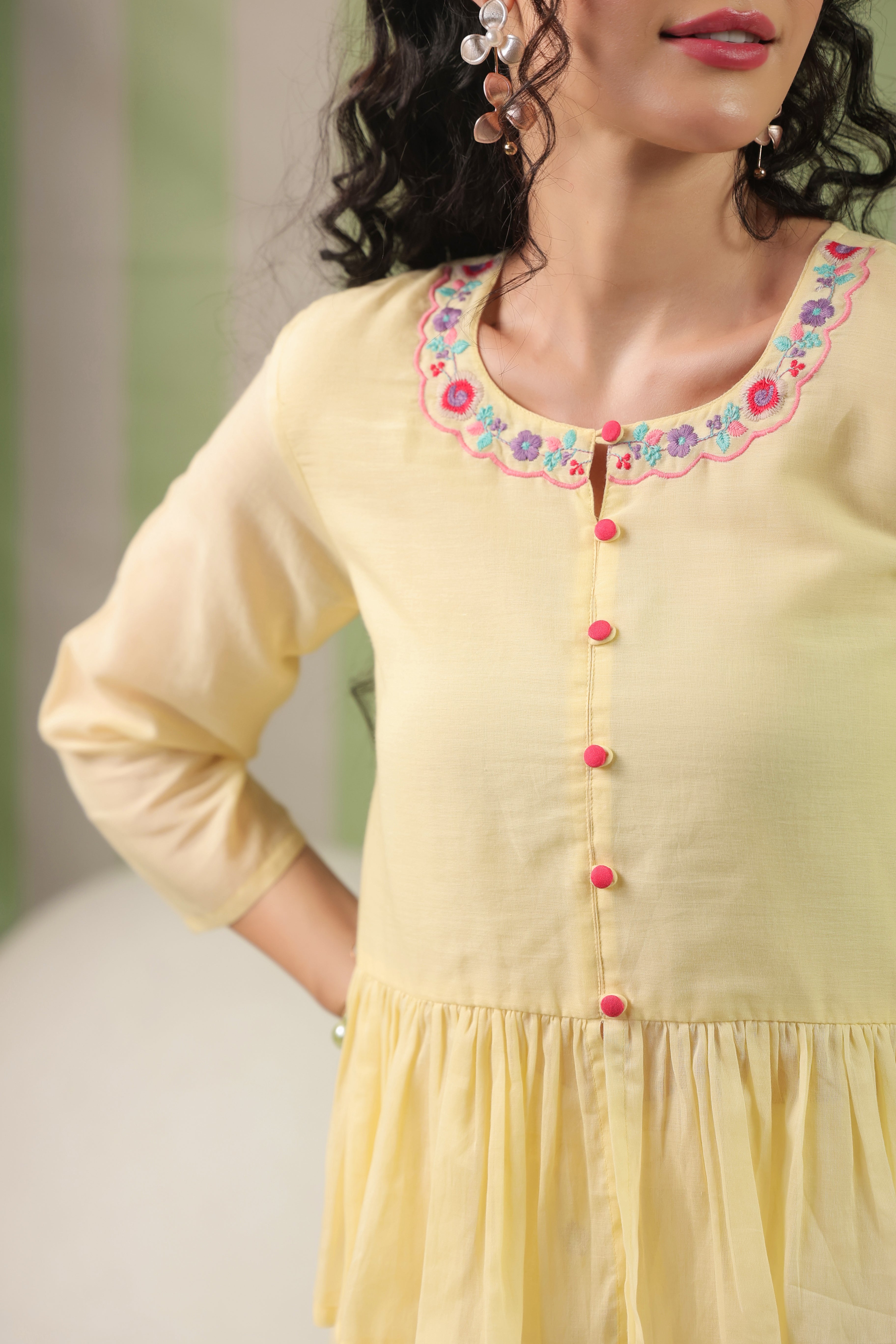 Woman wearing a blush yellow embroidered peplum co-ord set with wide-leg palazzo pants, featuring a floral embroidered neckline and relaxed elegant fit. Perfect for casual and festive occasions.