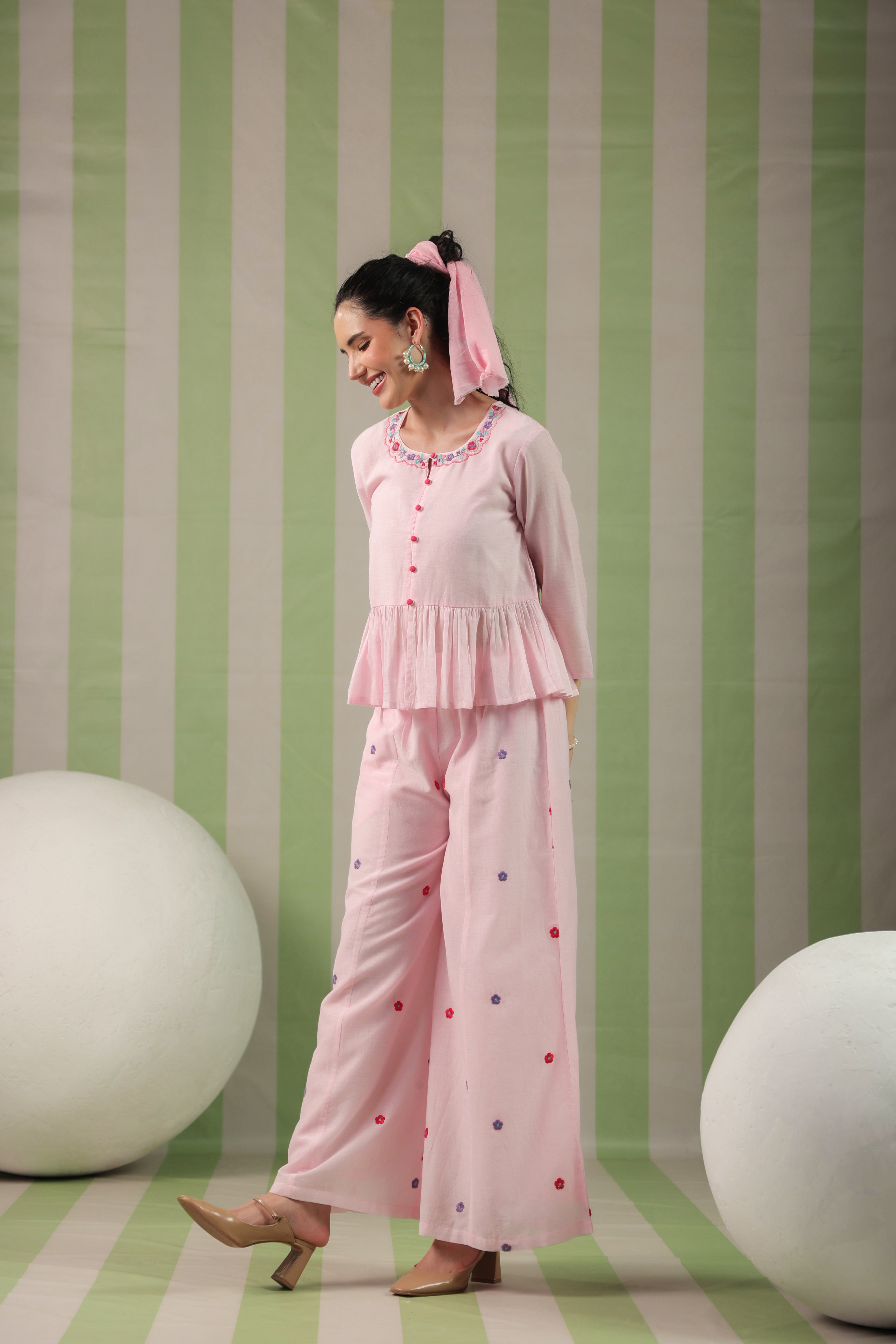 Woman in a pink outfit standing against a green and white striped background