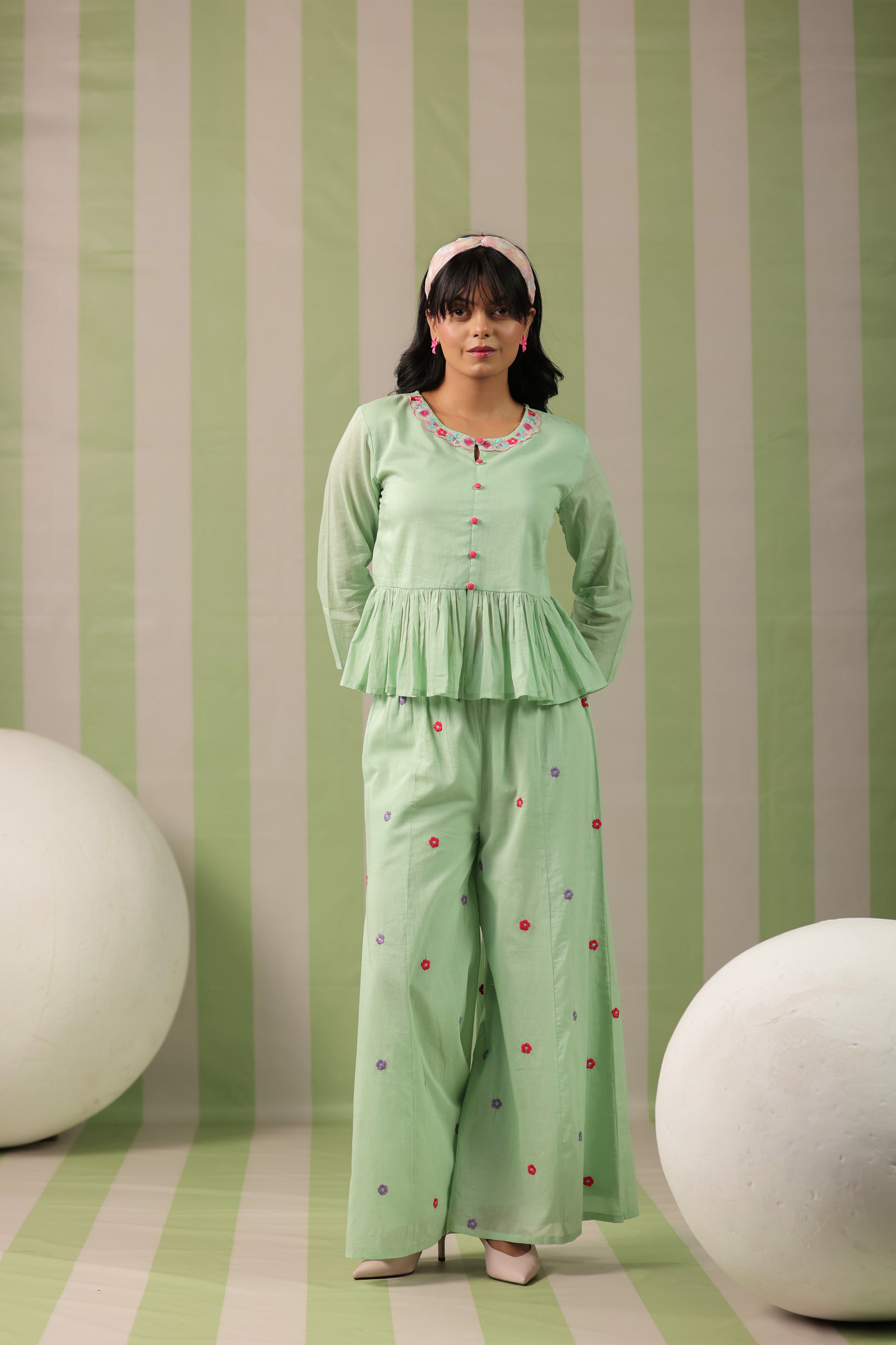 Woman wearing a pista green embroidered peplum co-ord set with wide-leg palazzo pants, round embroidered neckline, and floral detailing for ethnic casual wear