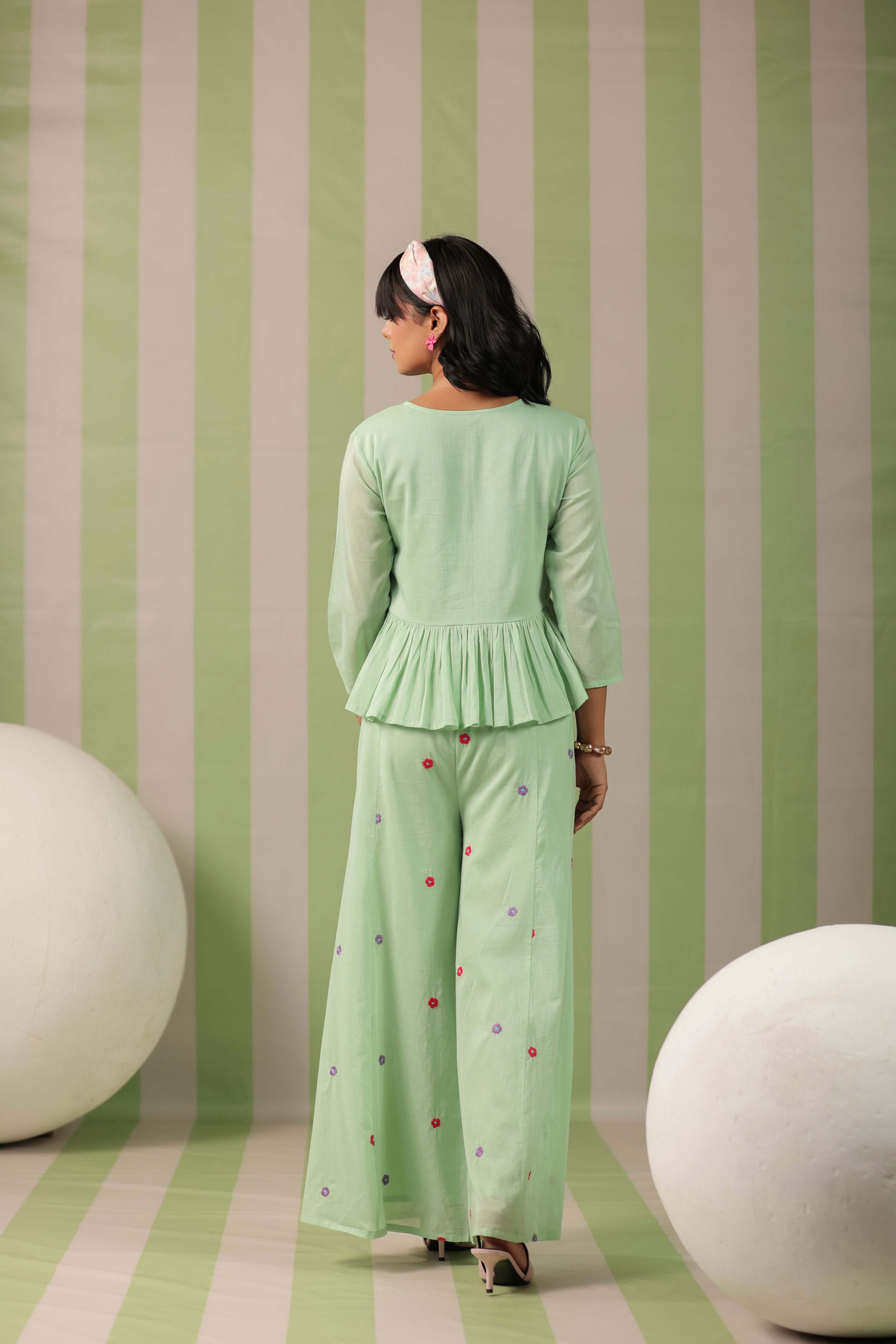 Woman wearing a pista green embroidered peplum co-ord set with wide-leg palazzo pants, round embroidered neckline, and floral detailing for ethnic casual wear