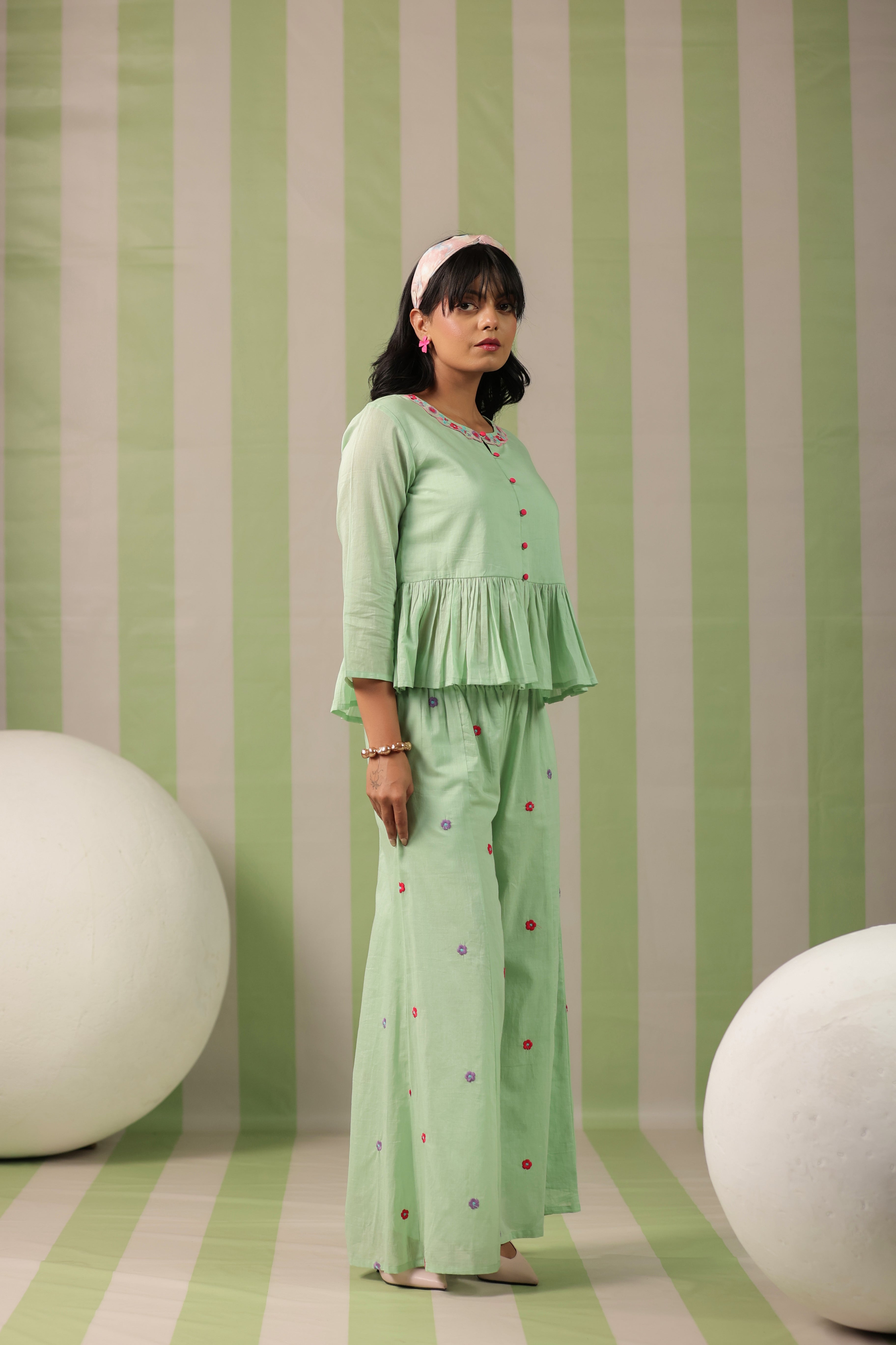 Woman wearing a pista green embroidered peplum co-ord set with wide-leg palazzo pants, round embroidered neckline, and floral detailing for ethnic casual wear
