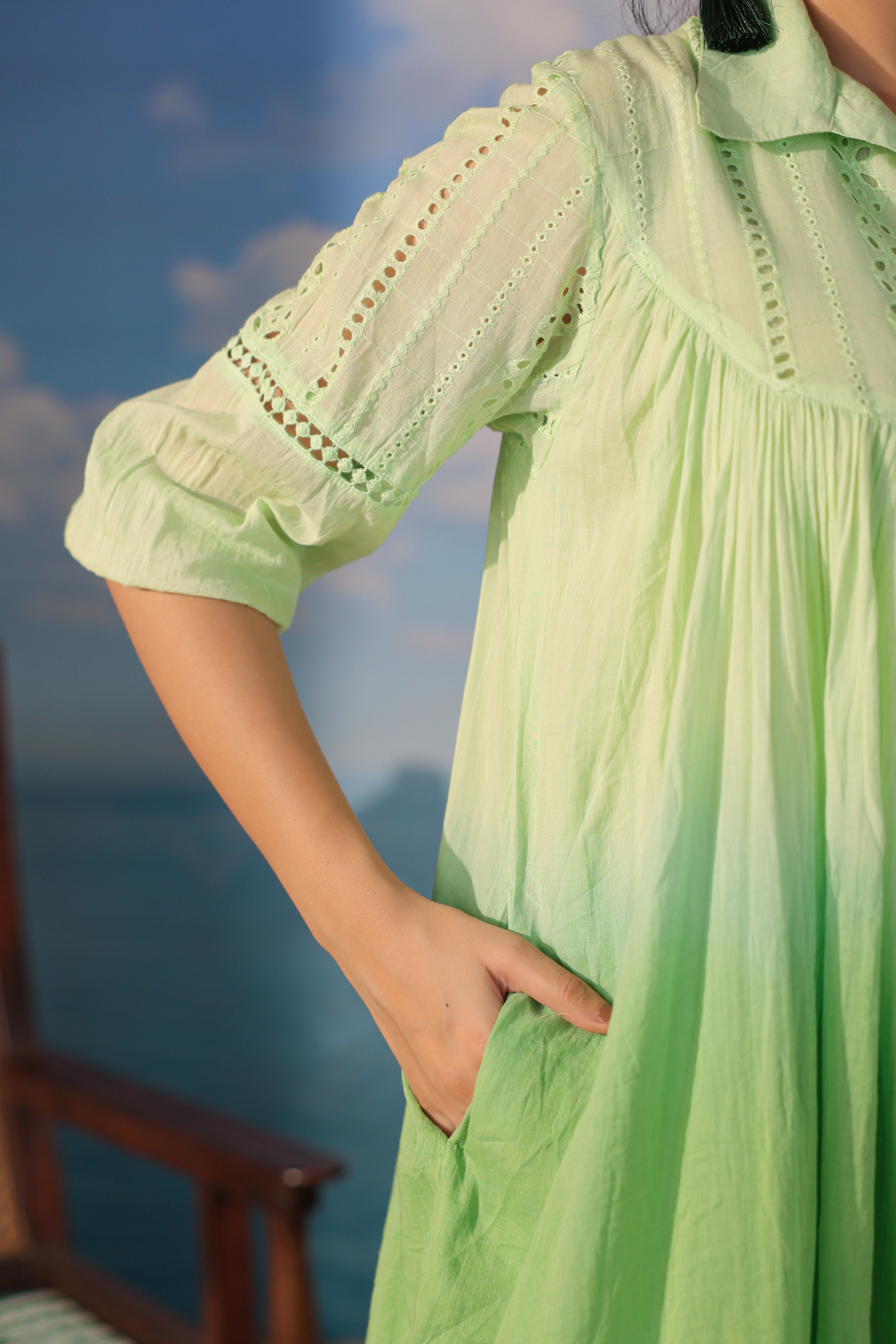 Person wearing a light green dress with a blurred blue background
