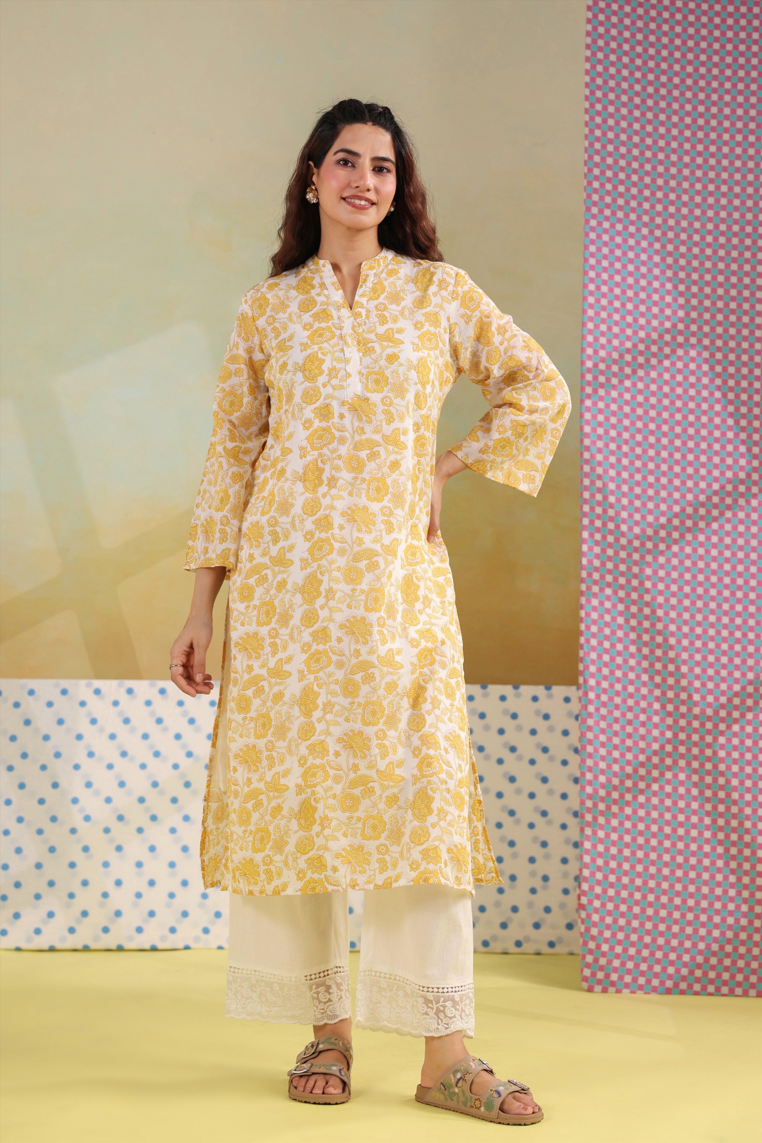 Woman wearing a yellow floral printed cotton straight kurta paired with a white lace palazzo, styled for casual and office ethnic wear.