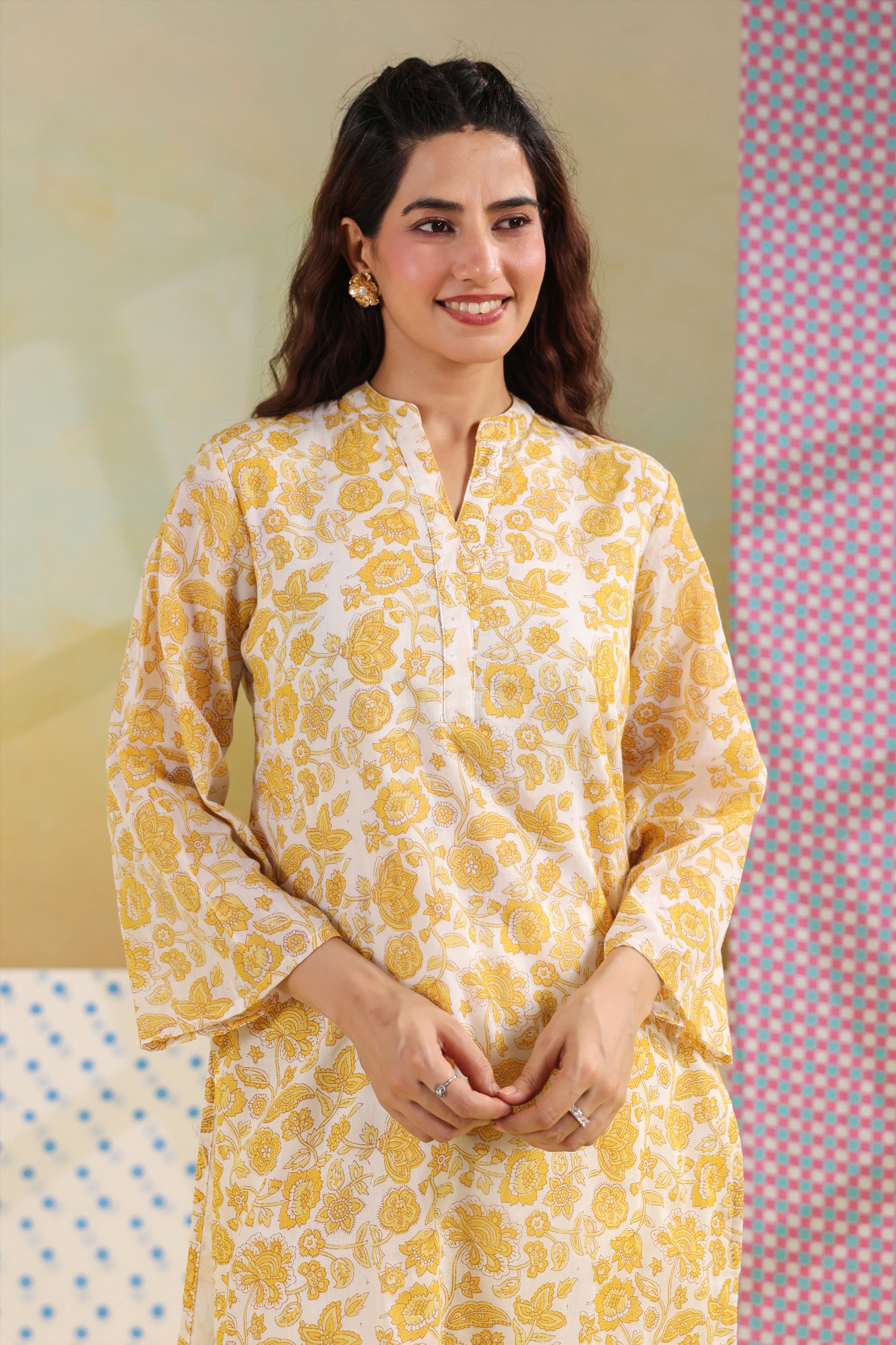 Woman wearing a yellow floral printed cotton straight kurta paired with a white lace palazzo, styled for casual and office ethnic wear.