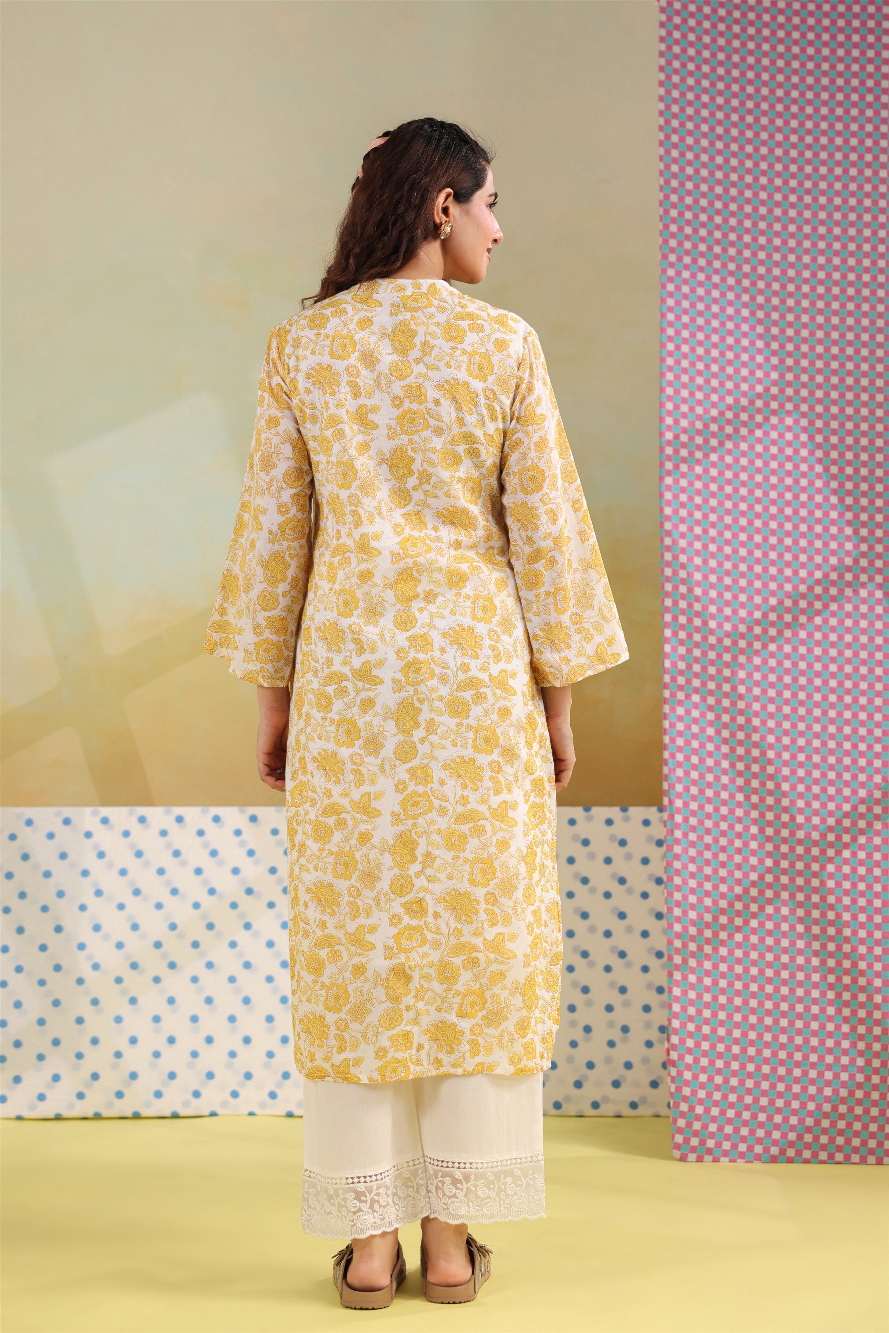 Woman wearing a yellow floral printed cotton straight kurta paired with a white lace palazzo, styled for casual and office ethnic wear.