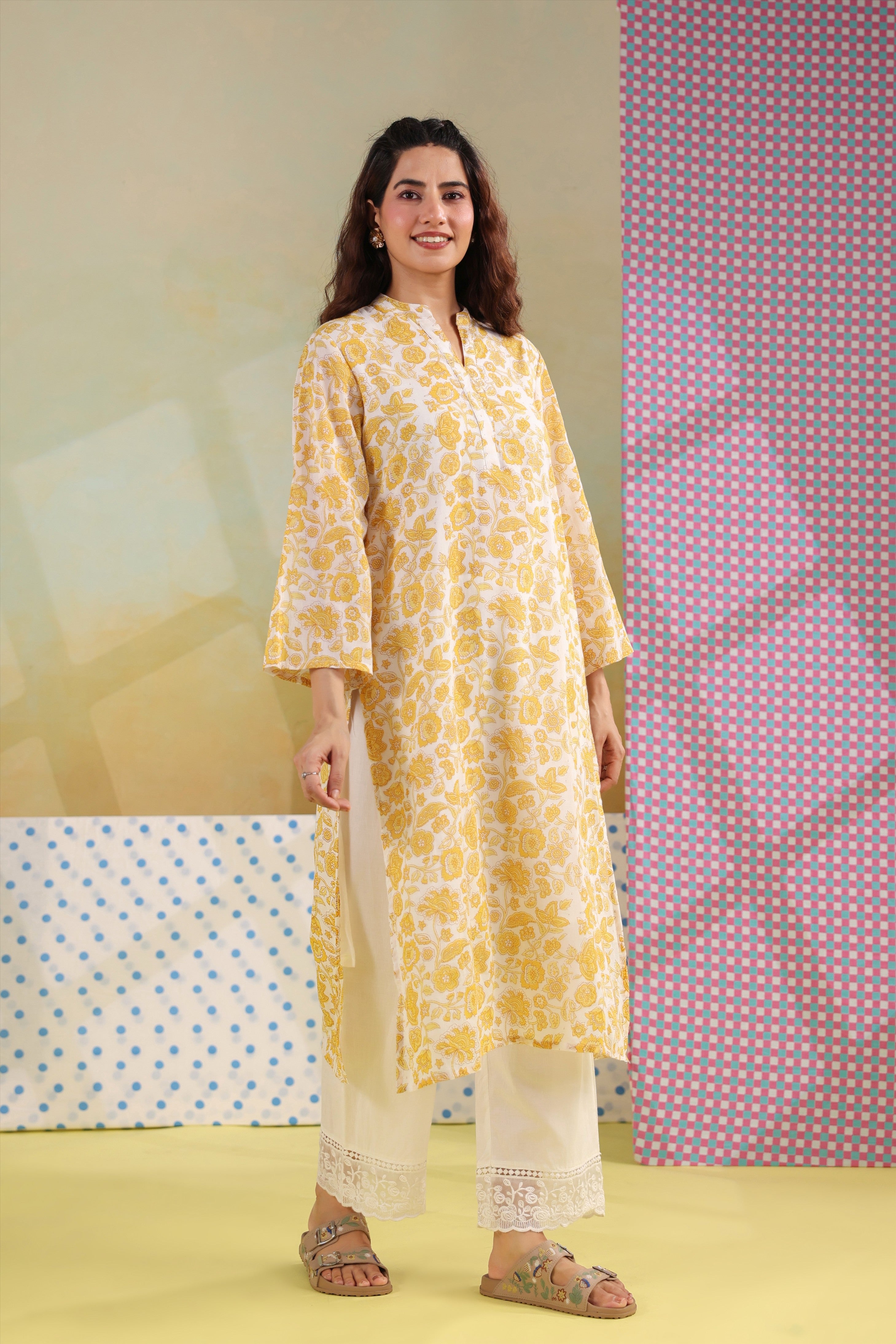 Woman wearing a yellow floral printed cotton straight kurta paired with a white lace palazzo, styled for casual and office ethnic wear.