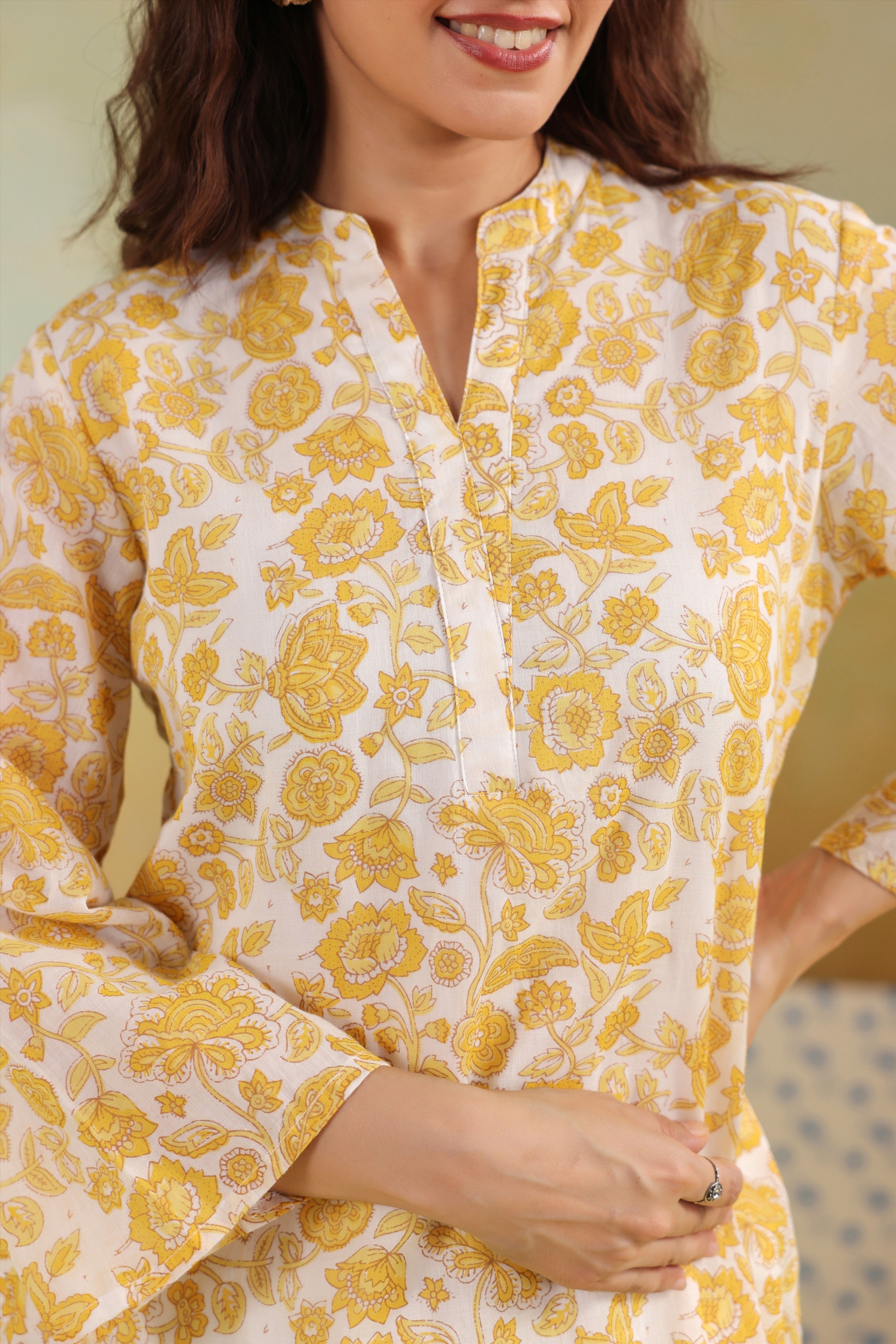 Woman wearing a yellow floral printed cotton straight kurta paired with a white lace palazzo, styled for casual and office ethnic wear.