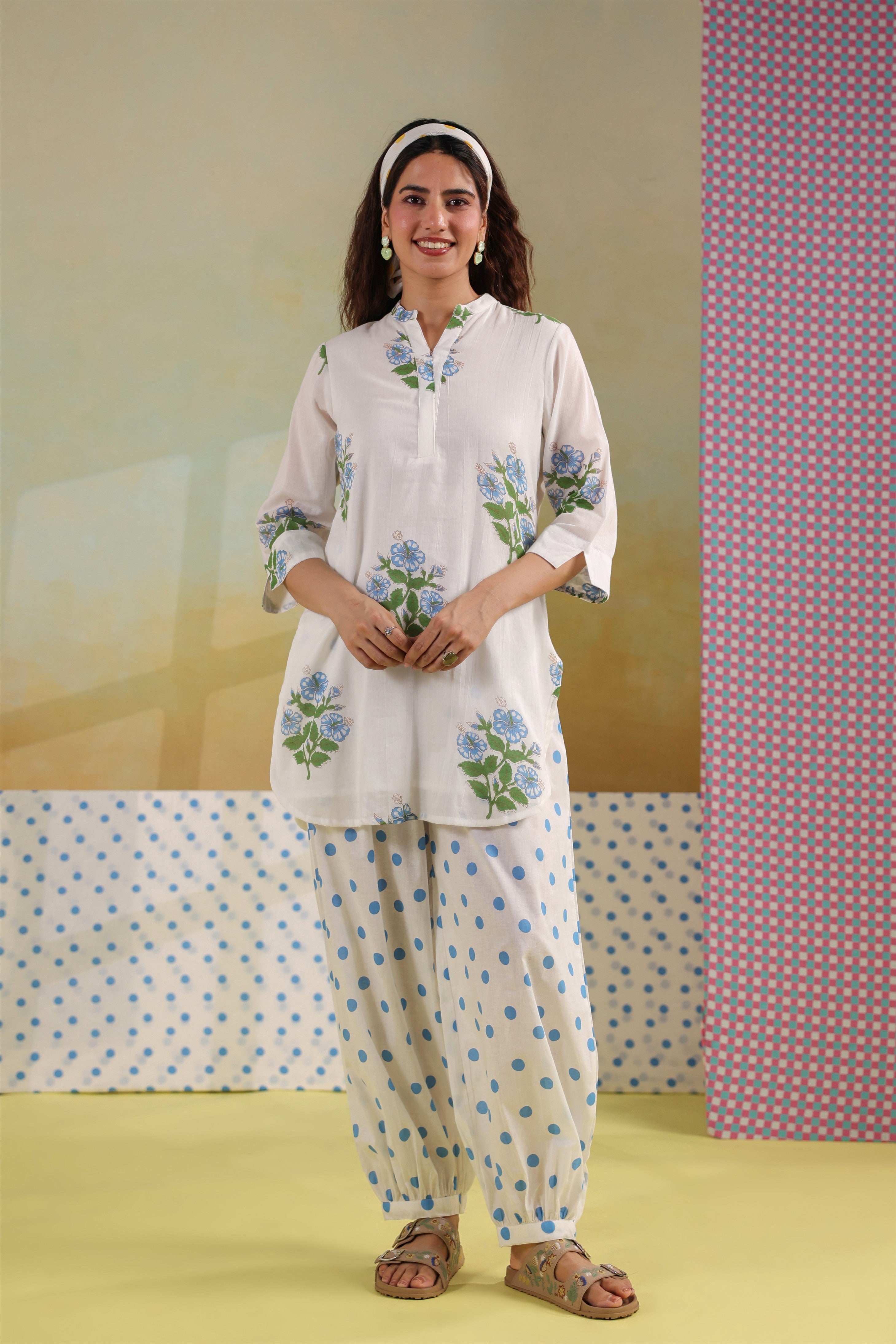 Woman wearing a white cotton floral printed co-ord set featuring a Mandarin collar top and blue polka dot balloon pants, ideal for casual, office, and summer wear.