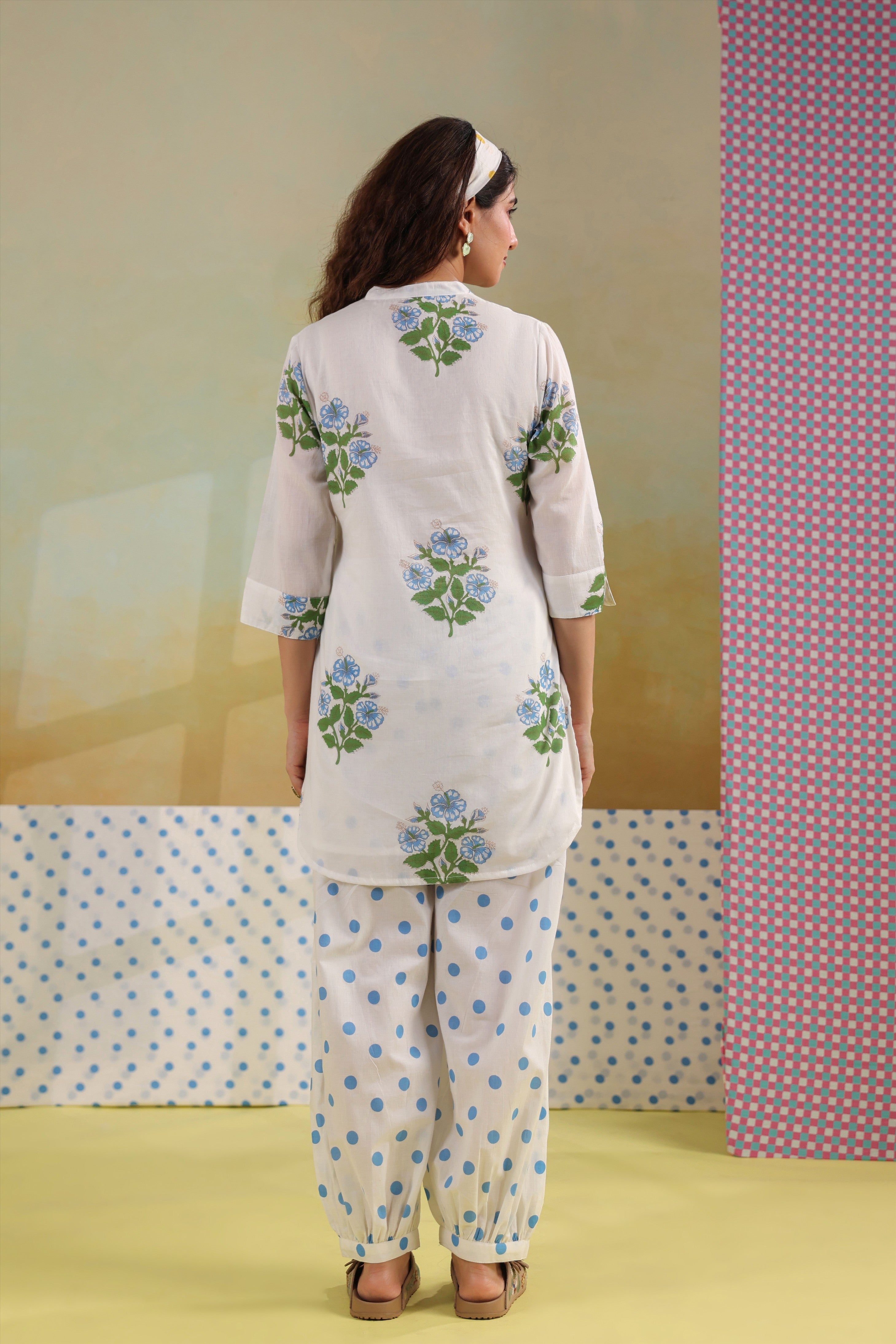 Woman wearing a white cotton floral printed co-ord set featuring a Mandarin collar top and blue polka dot balloon pants, ideal for casual, office, and summer wear.