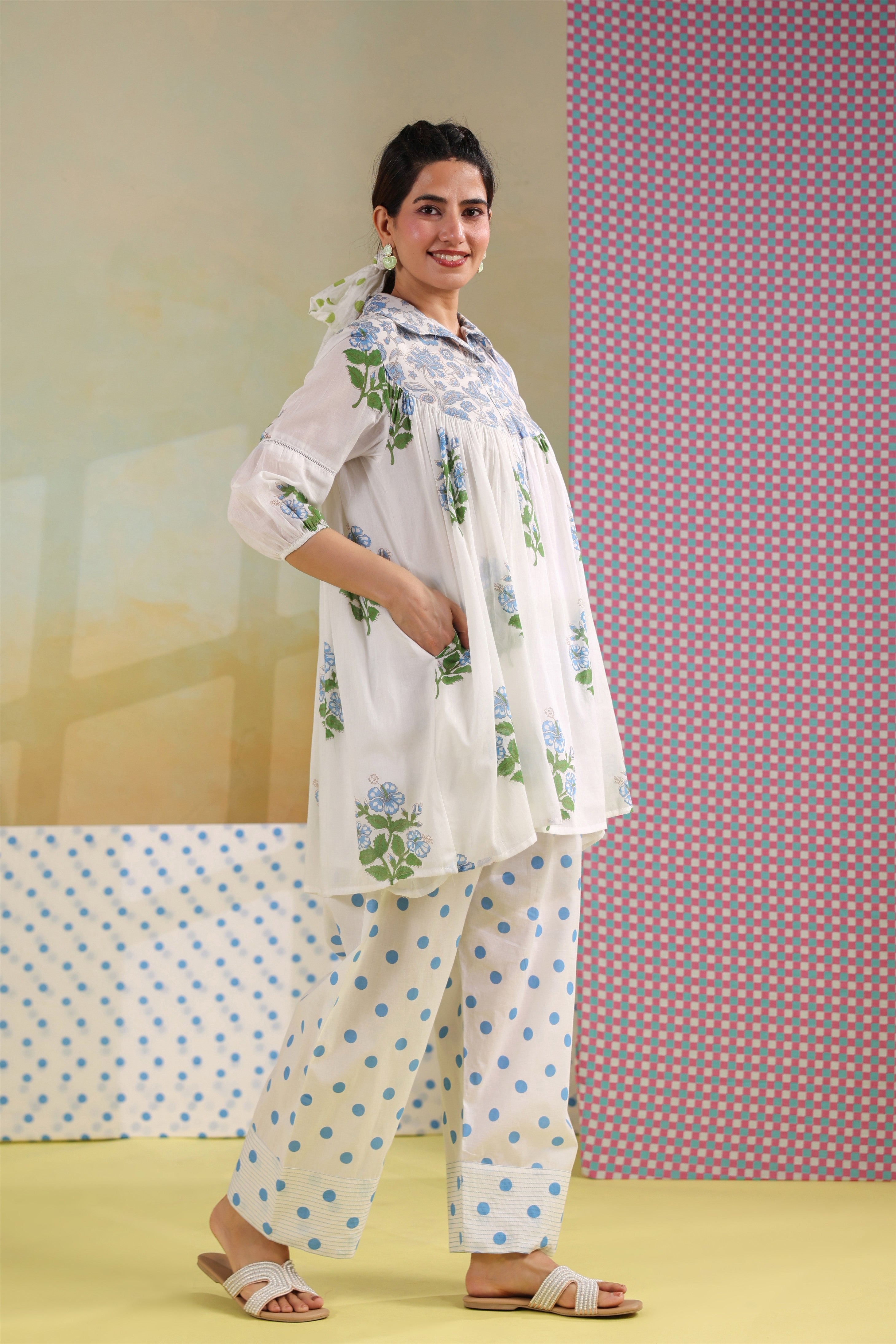 Woman wearing a white cotton gathered tunic with blue floral prints and a shirt collar, paired with blue polka dot straight pants, creating an elegant and comfortable co-ord set for casual, office, and summer wear.