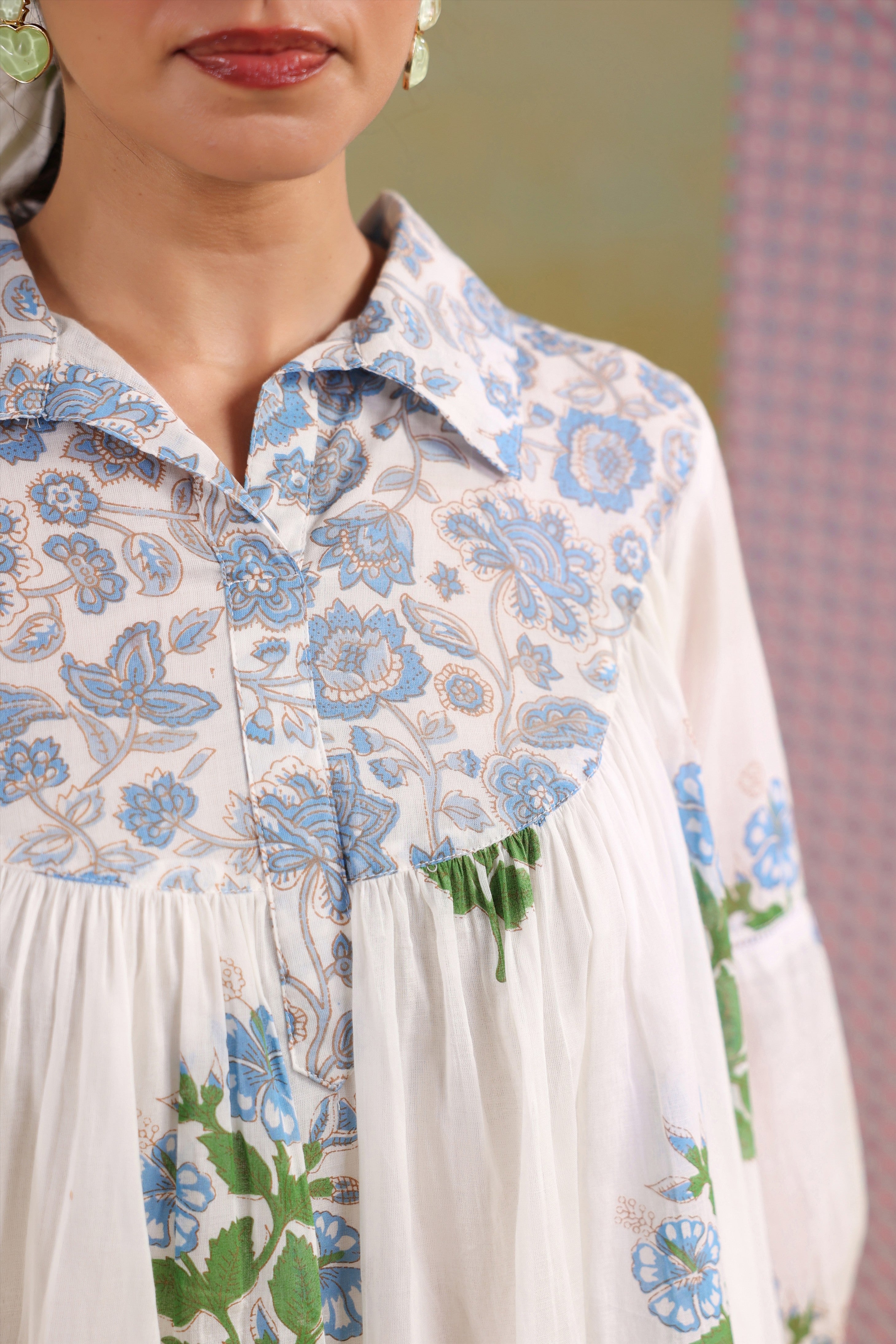 Woman wearing a white cotton gathered tunic with blue floral prints and a shirt collar, paired with blue polka dot straight pants, creating an elegant and comfortable co-ord set for casual, office, and summer wear.