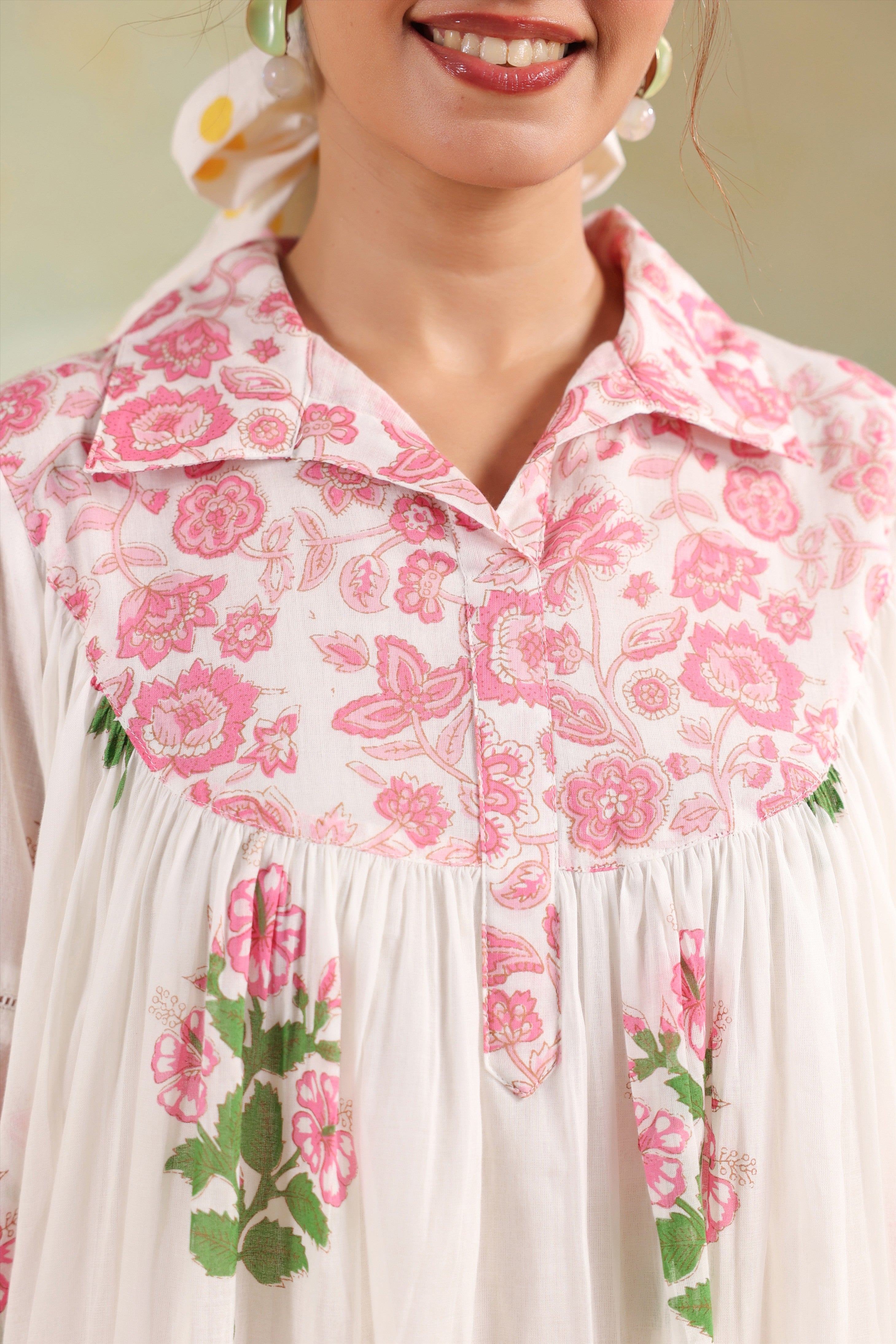 Woman wearing a white cotton floral printed gathered tunic with a shirt collar paired with pink polka dot straight pants, perfect for casual, office, and summer wear.