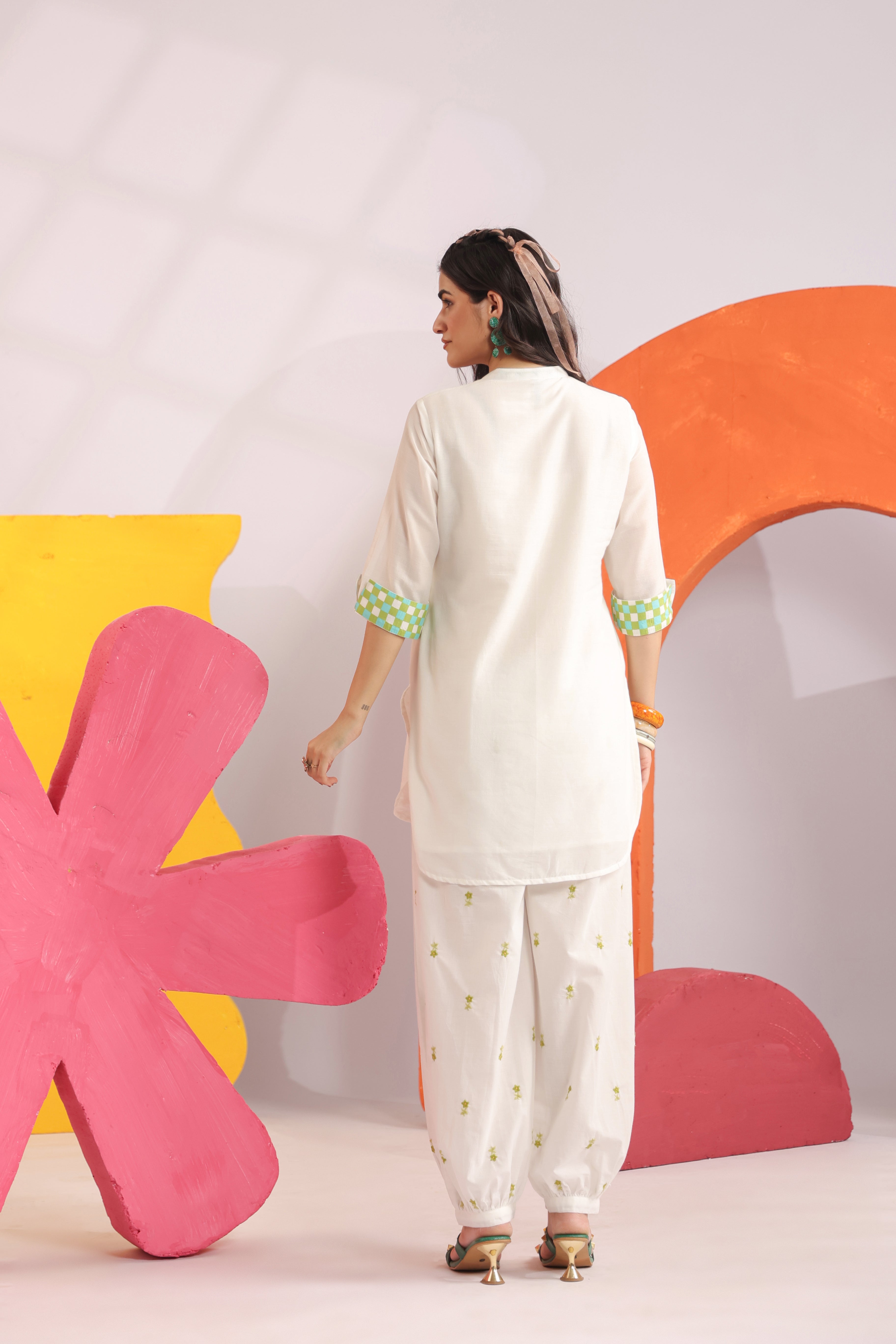 Woman wearing a white cotton embroidered straight-fit kurta with a Mandarin V-neck and contrast check sleeve cuffs, paired with white printed balloon pants, ideal for office wear, casual outings, and summer fashion.