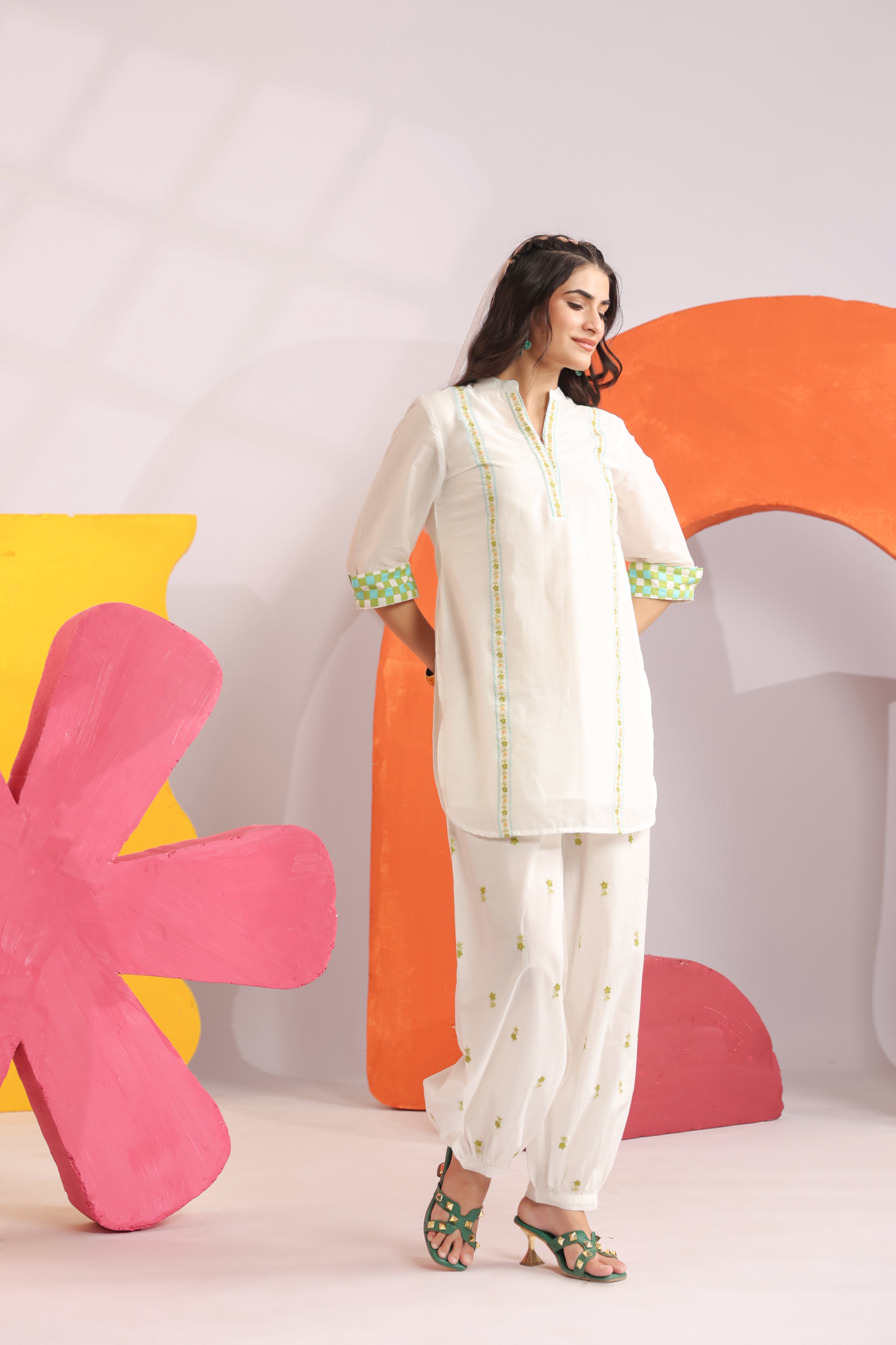 Woman wearing a white cotton embroidered straight-fit kurta with a Mandarin V-neck and contrast check sleeve cuffs, paired with white printed balloon pants, ideal for office wear, casual outings, and summer fashion.