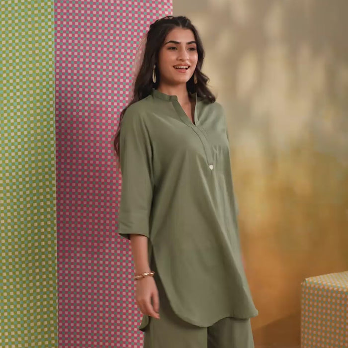 Woman wearing a sage green cotton co-ord set featuring a relaxed-fit straight kurta with a mandarin V-neck and matching elasticated jogger pants, ideal for casual, office, and everyday wear.