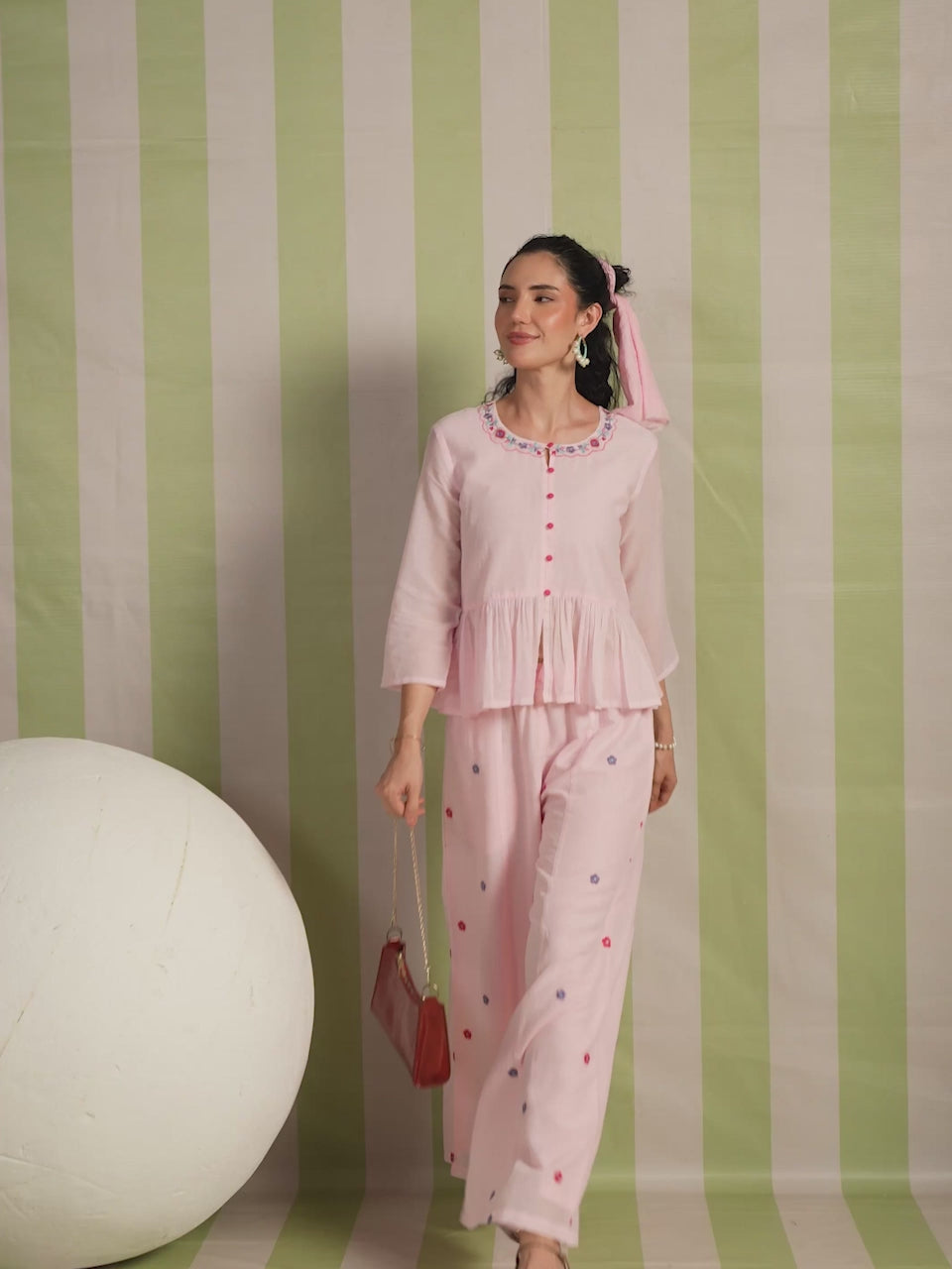 Woman wearing a blush pink  embroidered peplum co-ord set with wide-leg palazzo pants, featuring a floral embroidered neckline and relaxed elegant fit. Perfect for casual and festive occasions.