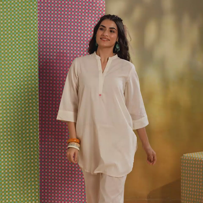 Woman wearing an ivory cotton co-ord set featuring a relaxed-fit straight kurta with a mandarin V-neck and matching elasticated jogger pants, offering a minimalist and elegant look for casual, office, and everyday wear.